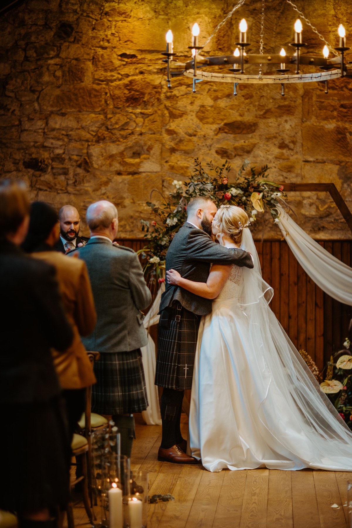 first kiss of bride wearing white lace dress and groom wearing full kilt outfit as guests look on scottish humanist wedding