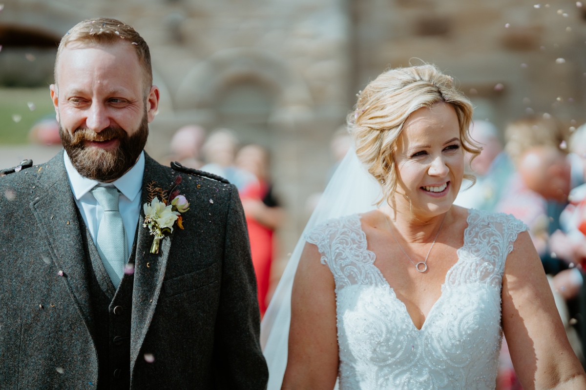 just married bride and groom smiling as they walk past guests throwing confetti rosebery steadings wedding