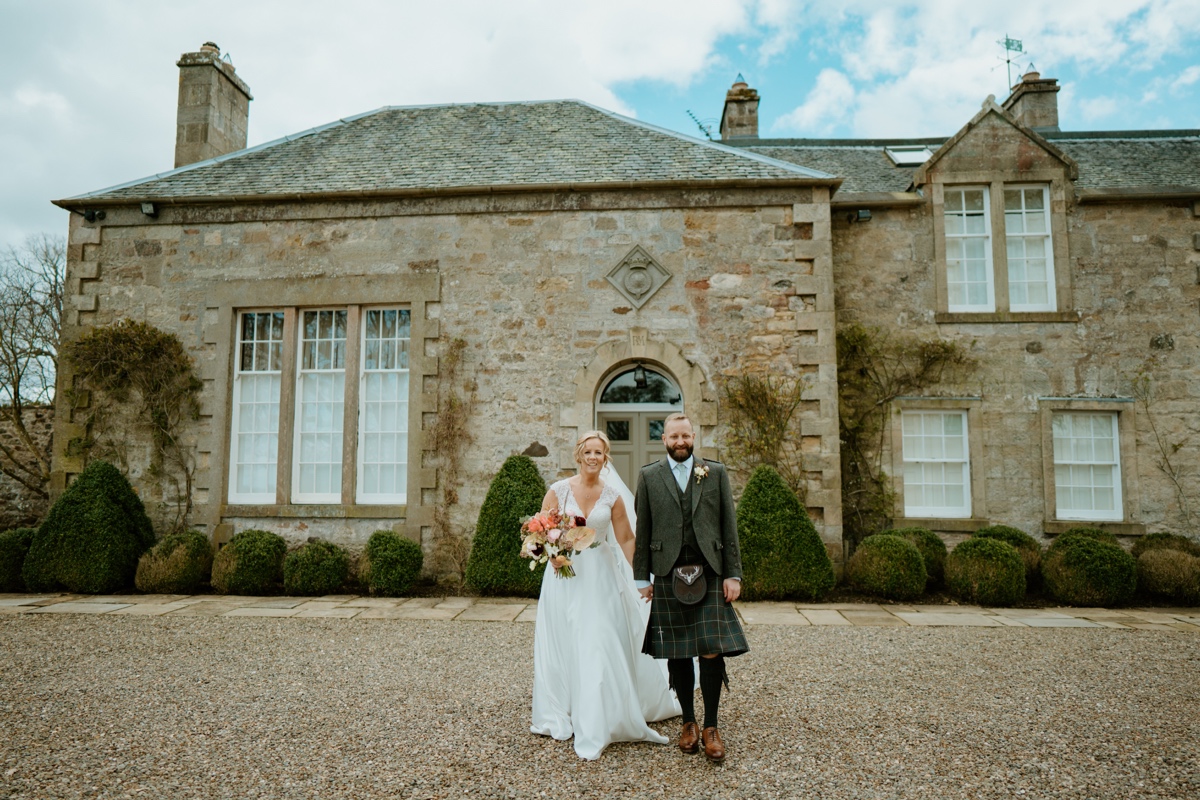 bride and groom holding hands facing camera outside of Rosebery Steadings in Gorebridge, an exclusive use Scottish wedding venue