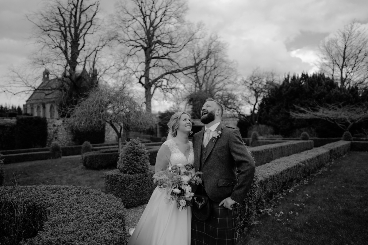 black and white photo of bride and groom holding each other and laughing in gardens of rosebery steadings scottish humanist wedding