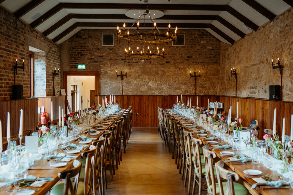 picture of the dining hall at rosebery steadings wedding with two long tables with candles and flowers scottish wedding photography