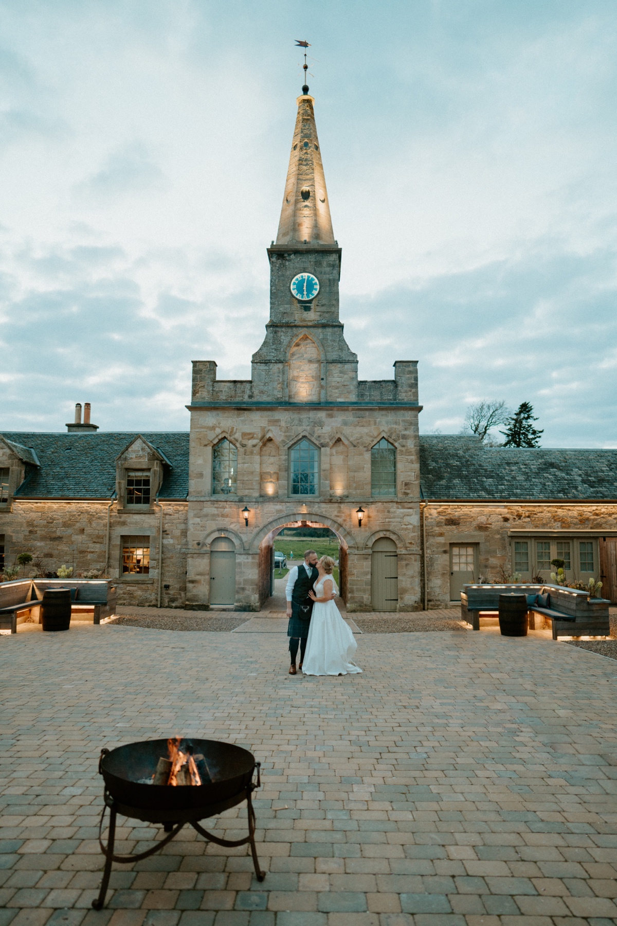 bride and groom kissing in courtyard of rosebery steadings in front of clock tower scottish humanist wedding