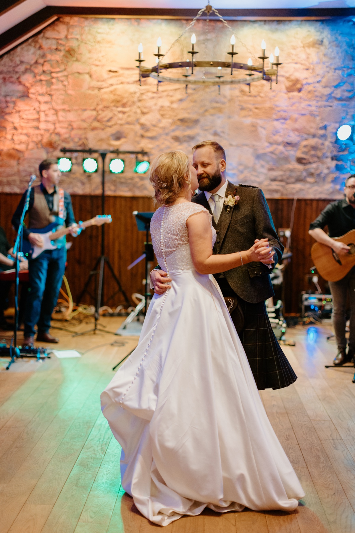 bride wearing white dress and groom wearing kilt outfit first dance with band in background scottish humanist wedding
