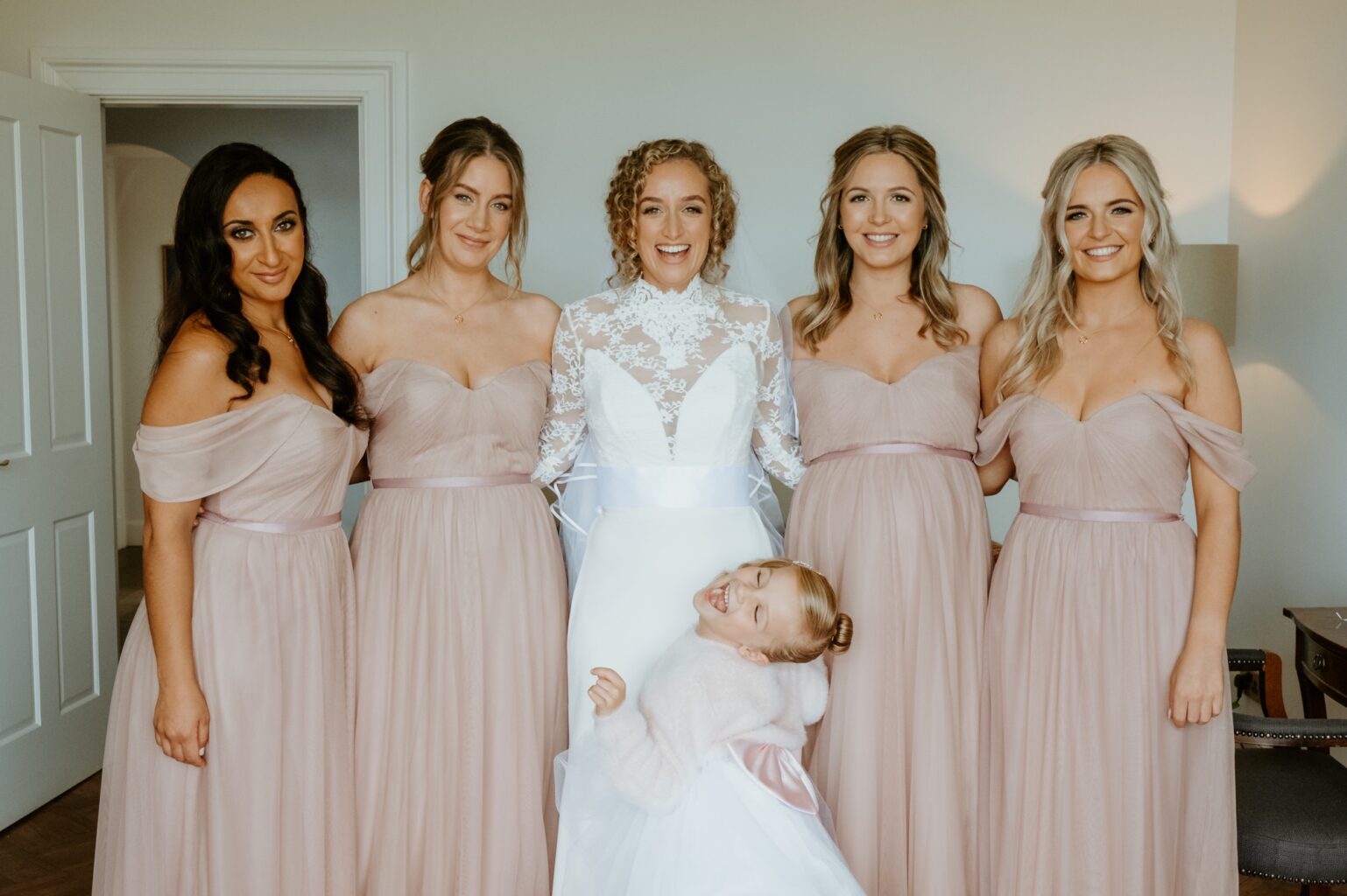 bride wearing white lace dress with bridesmaids and flower girl all facing camera cairns farm estate wedding