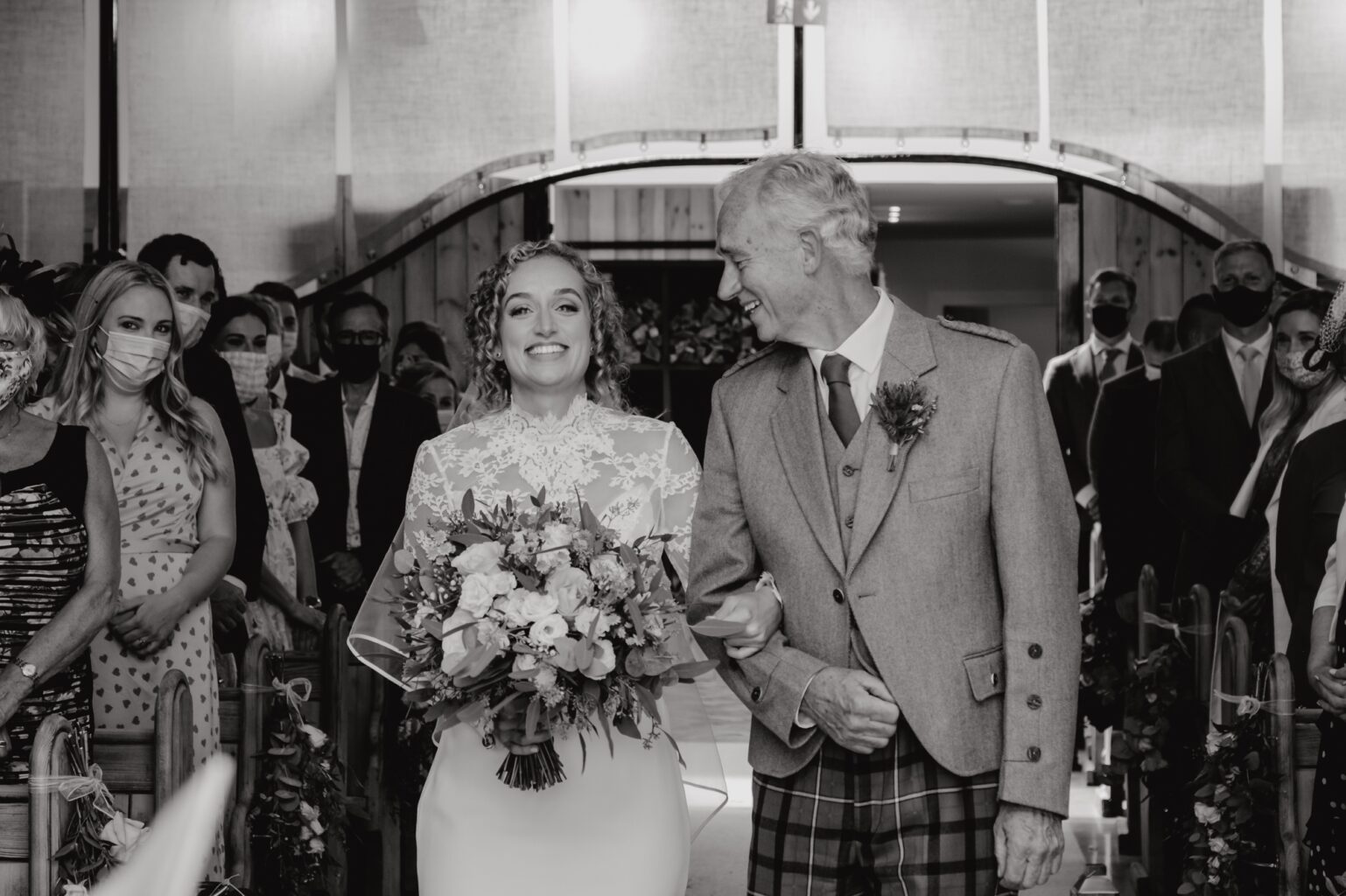 black and white photo of bride being walked down the aisle by her dad as he smiles at her cairns farm estate wedding
