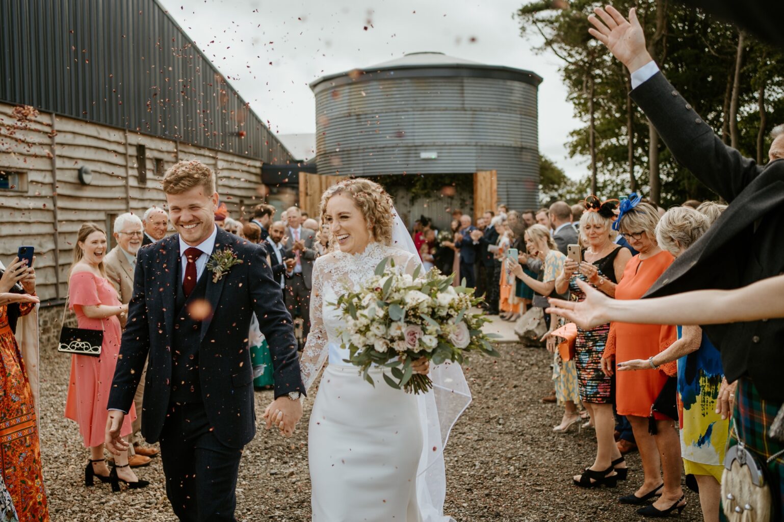 bride and groom walking towards camera being showered in confetti as they walk through guests cairn farm estate wedding