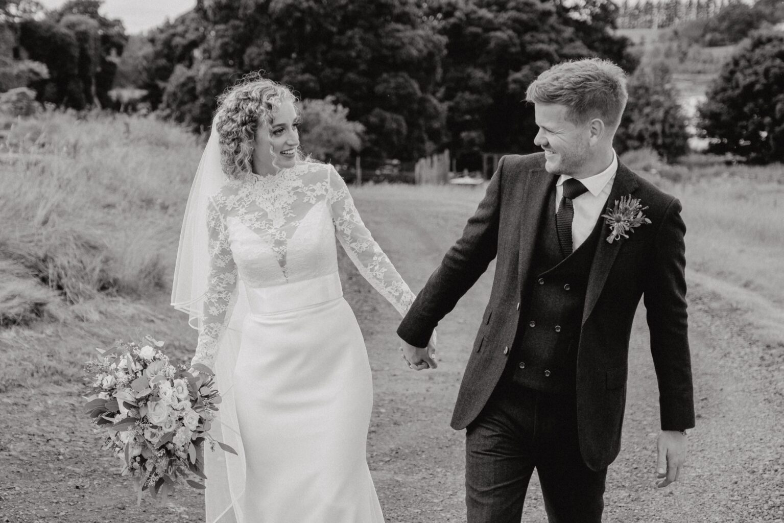 black and white photo of ride and grom walking hand in hand as they look lovingly into each others eyes cairns farm estate wedding