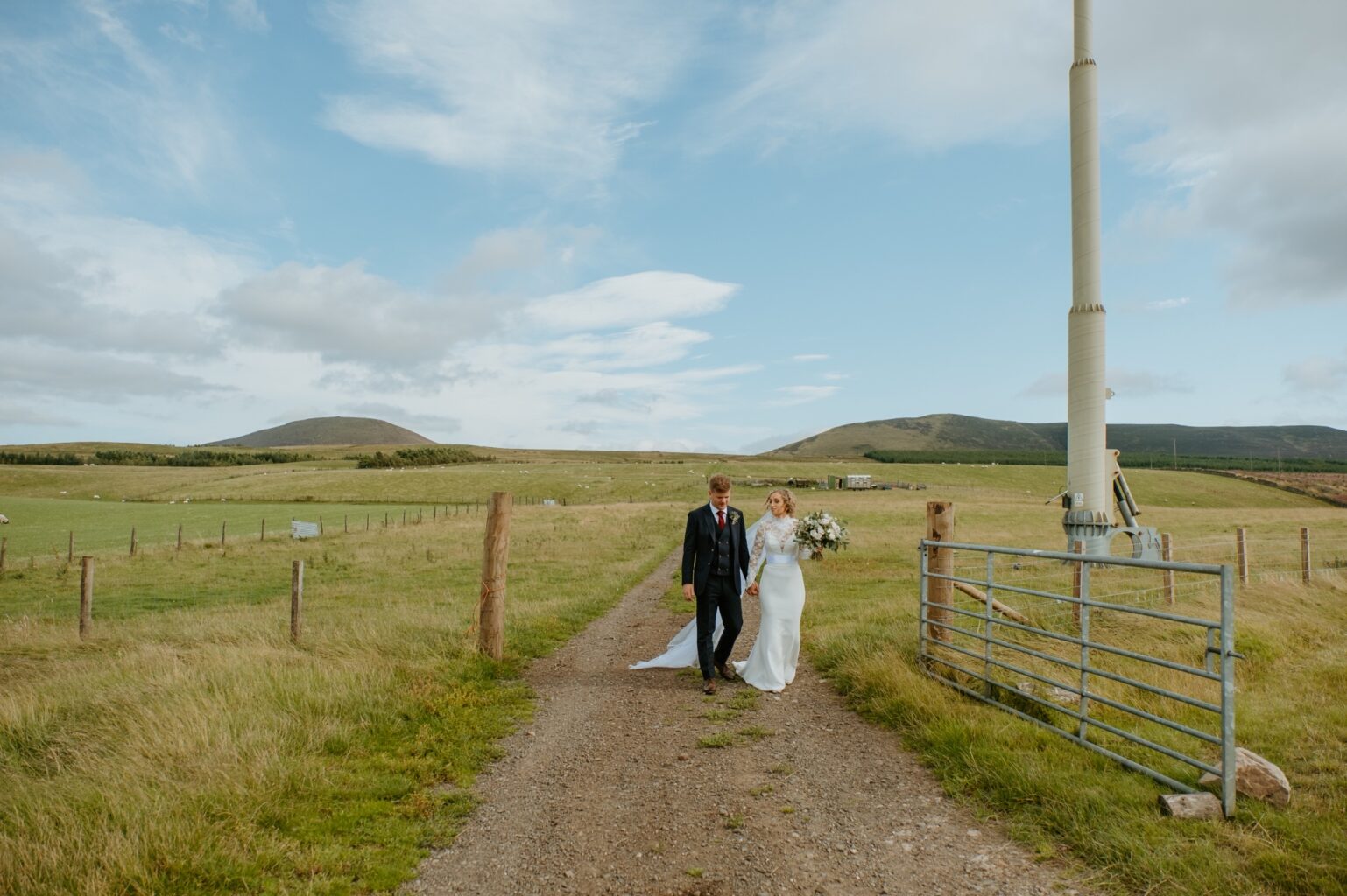 bride and groom walking towards camera on mud road through a green field cairns farm estate wedding