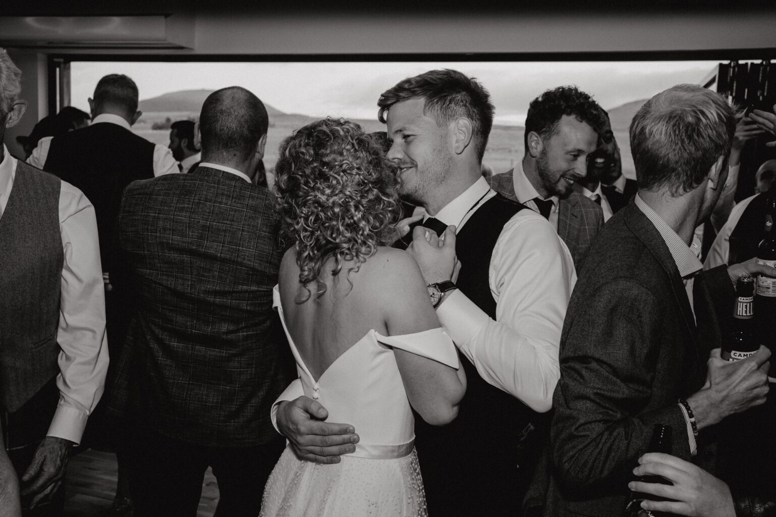 black and white photo of bride and groom slow dancing with guests dancing in background cairns farm estate wedding