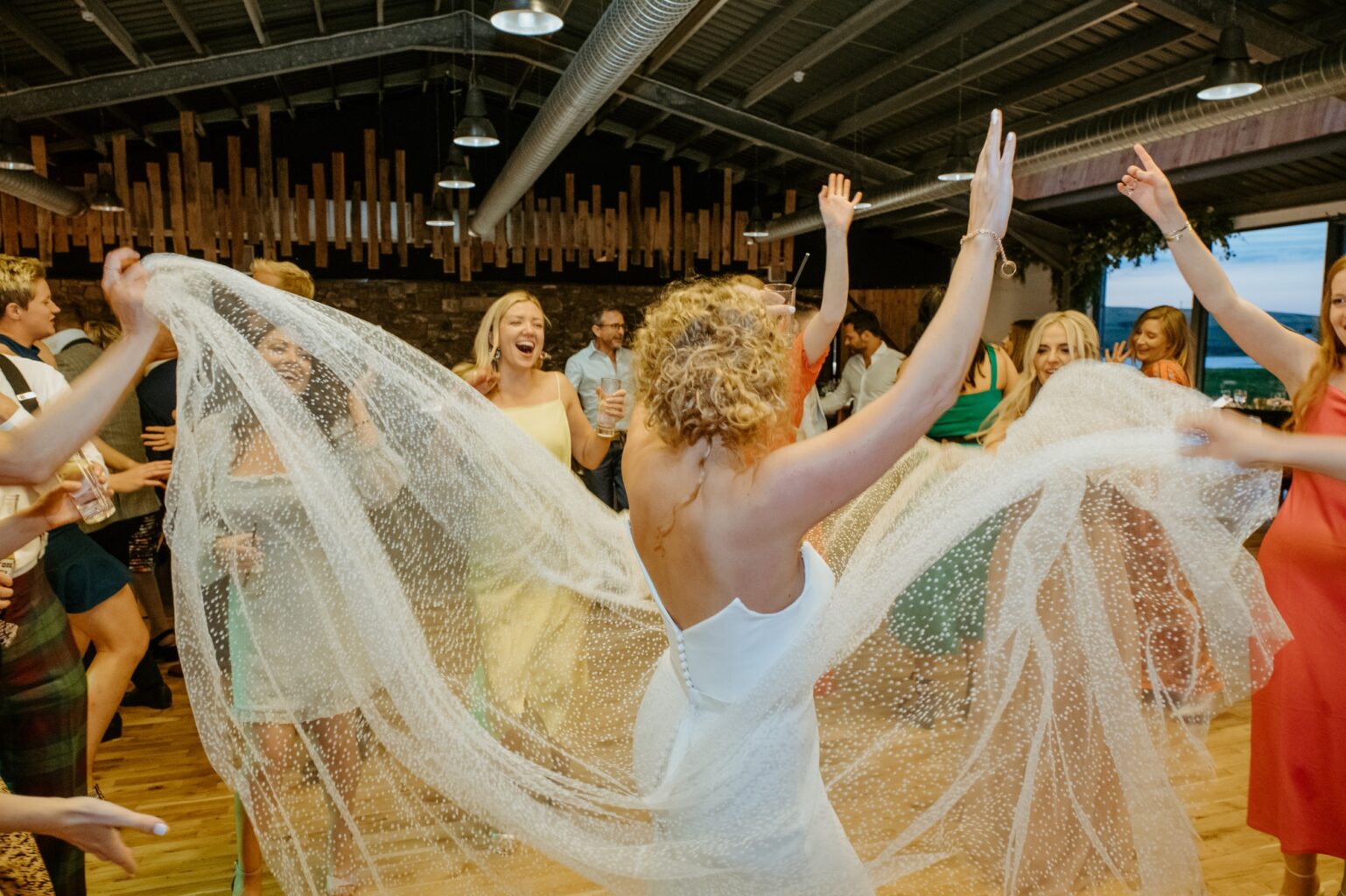 bride dancing with her hands in the air as guests hold up her wedding dress cairns farm estate wedding