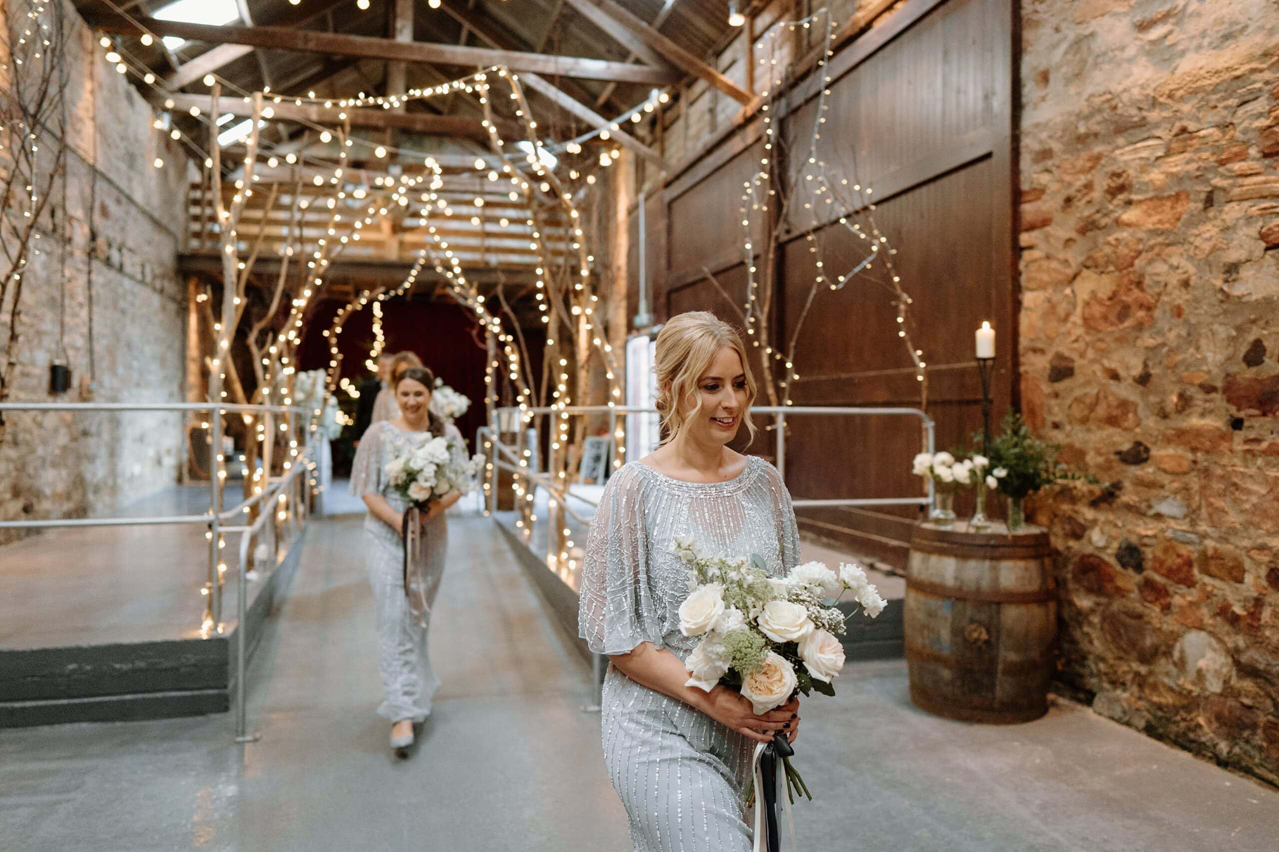 kinkell byre wedding photos bridesmaids in silver sparkly dresses walking down hall to wedding ceremony