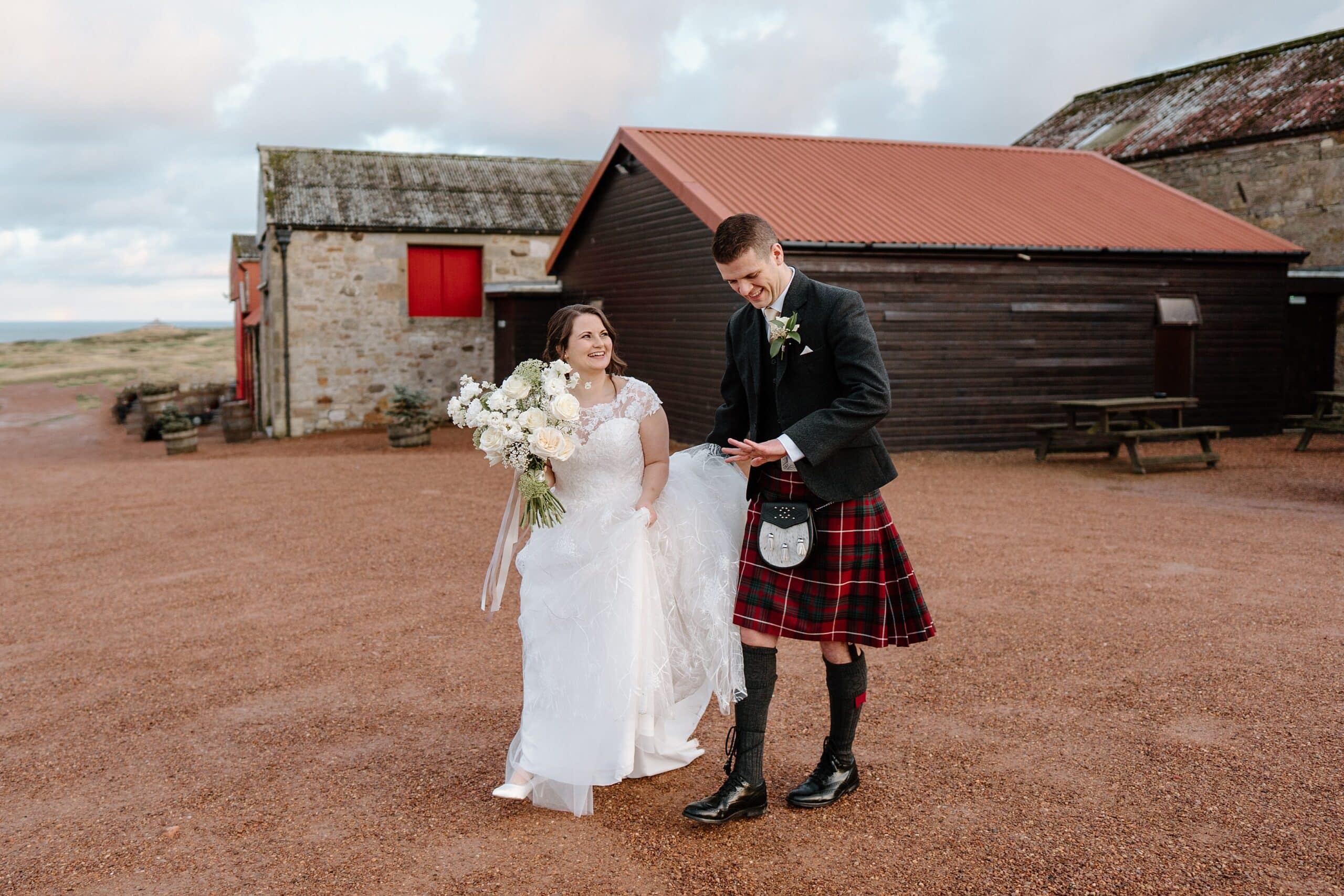 kinkell byre wedding photos exterior outside view of farm barn wedding venue st andrews scotland bride and groom walking away from venue