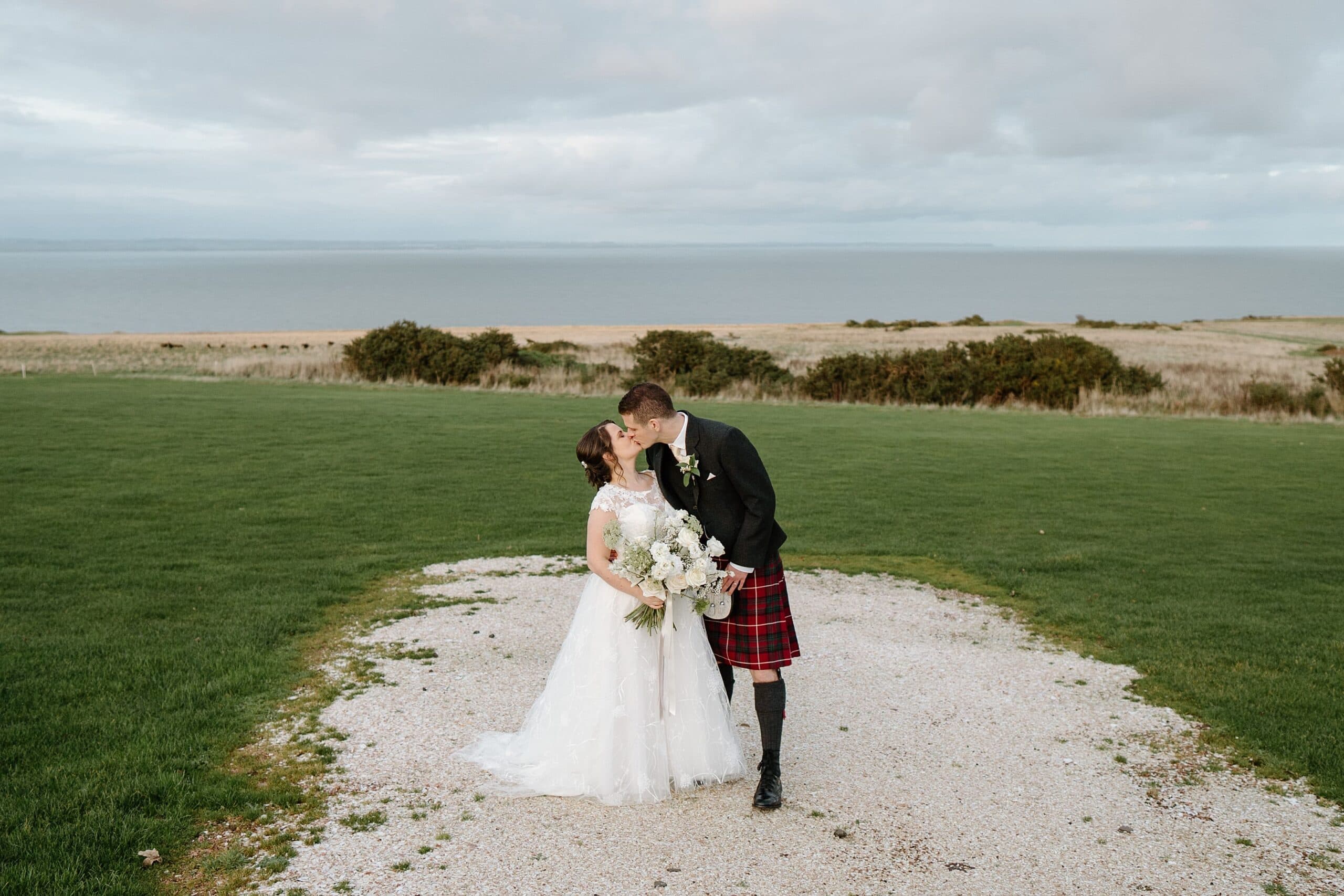 kinkell byre wedding photos of bride and groom outside venue with beach in the background