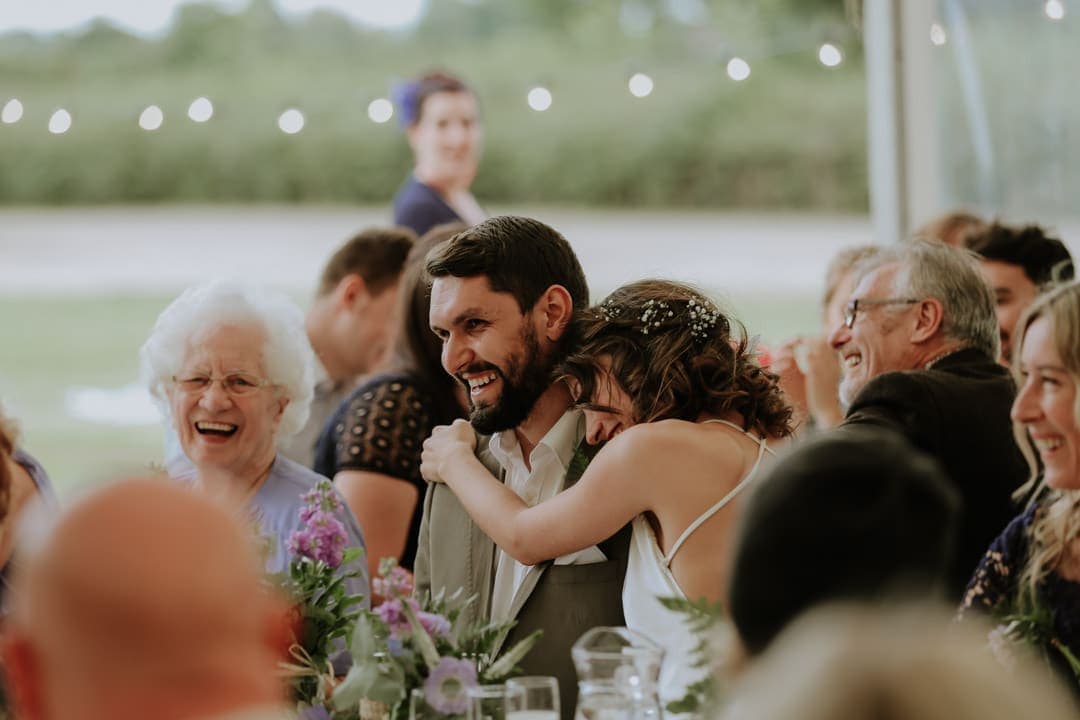 bride-hugs-laughing-groom-diy-marquee-wedding-leicestershire-wedding-photographer