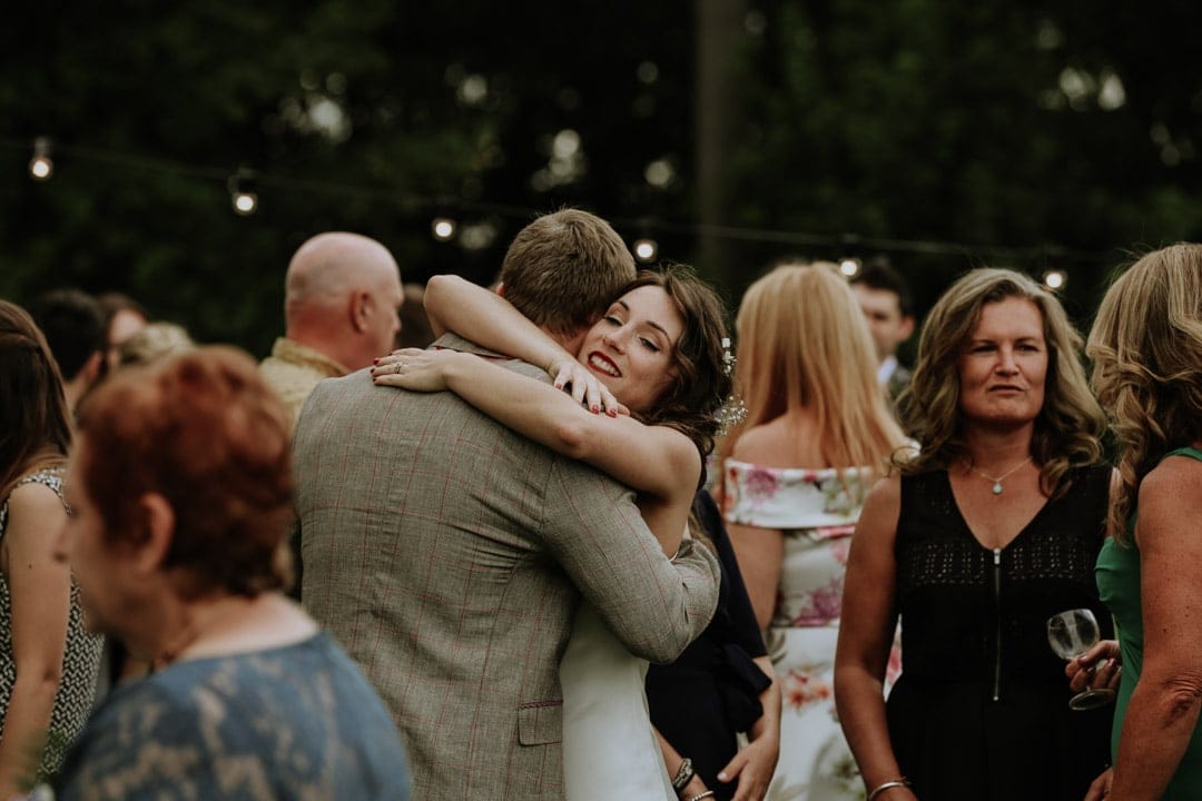 bride-wearing-red-lipstick-hugs-guest-smiling-leicester-wedding