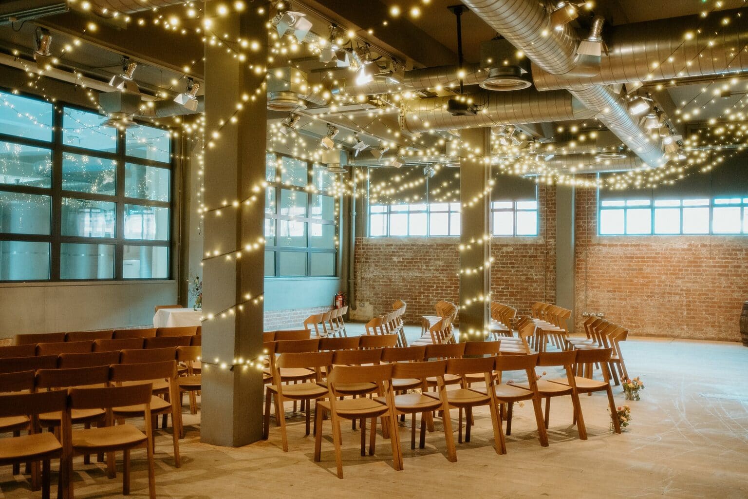 ceremony setup inside brewery with wooden chairs and fairy lights west on the green wedding glasgow