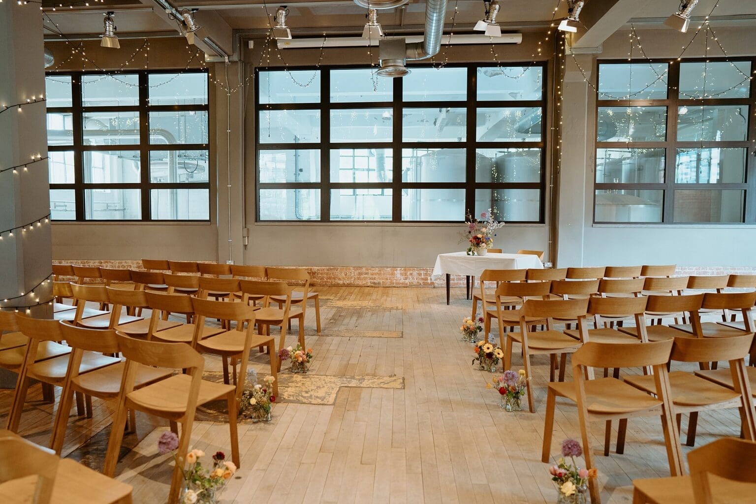 ceremony setup inside brewery with wooden chairs at either side of aisle west on the green wedding unique wedding venues glasgow