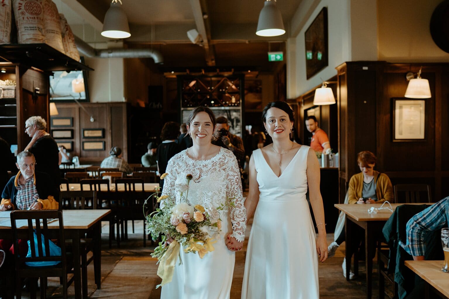 brides wearing white dresses holding hands in bar west on the green wedding unique wedding venues glasgow