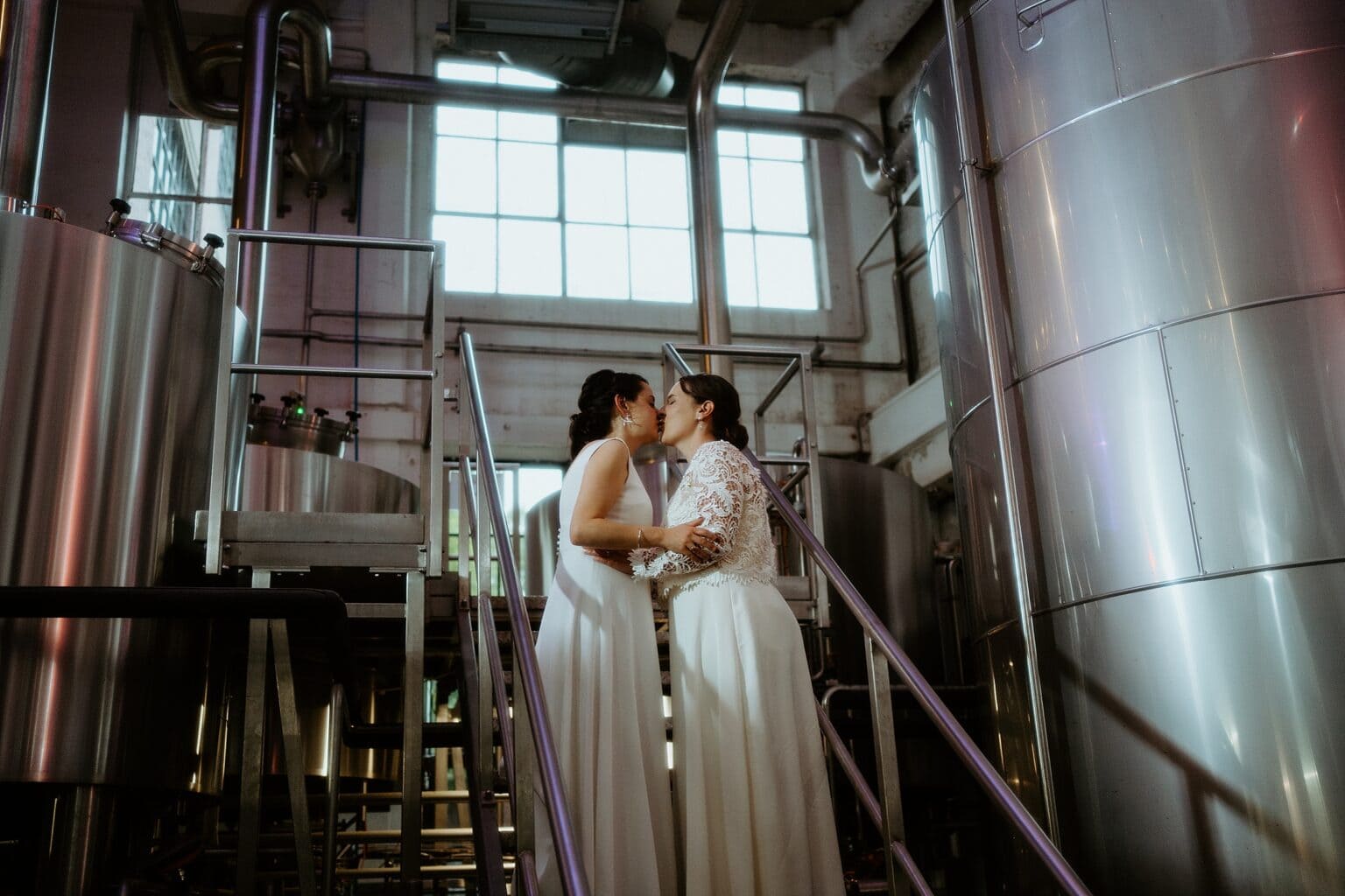 brides kissing on metal steps inside brewery west on the green wedding exclusive use wedding venues scotland