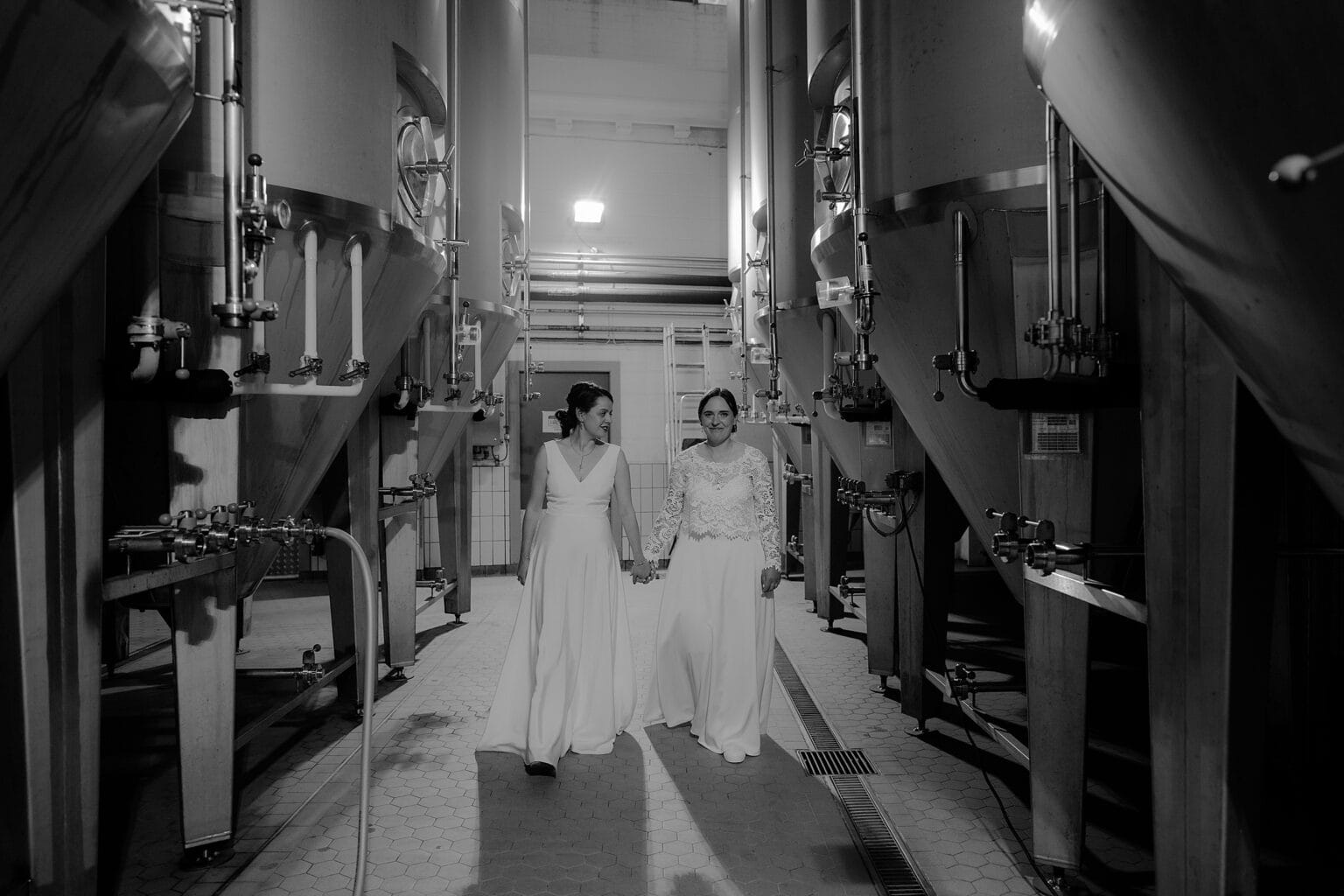 black and white photo of brides holding hand walking towards the camera in brewing room west on the green wedding