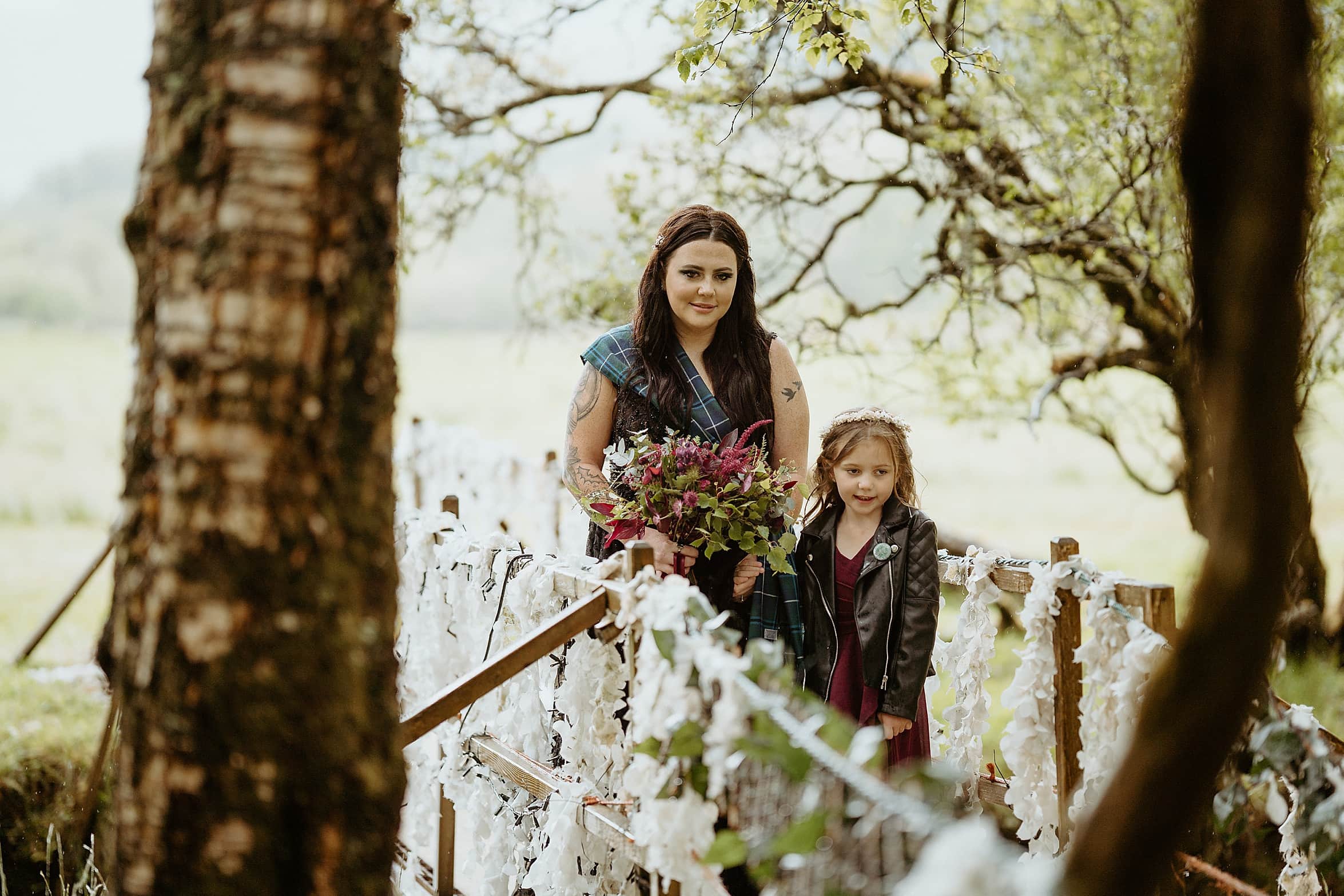 bride to be and daughter walking over small wooden bridge in woodland monachyle mhor wedding