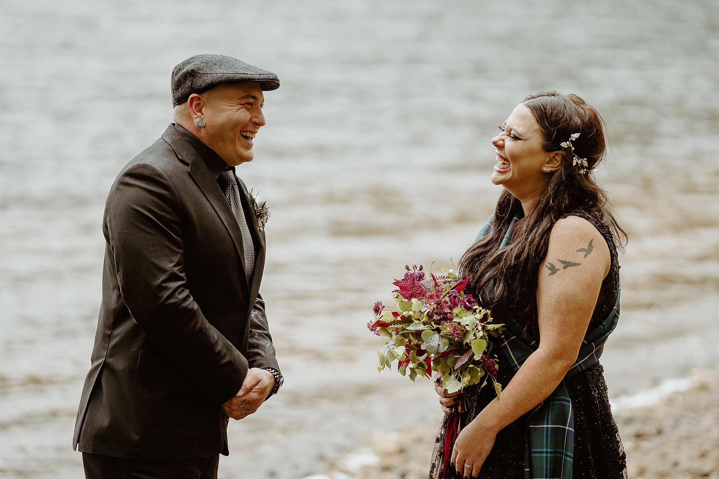 bride and groom laughing as thy face each other at lochside ceremony both wearing black monachyle mhor wedding