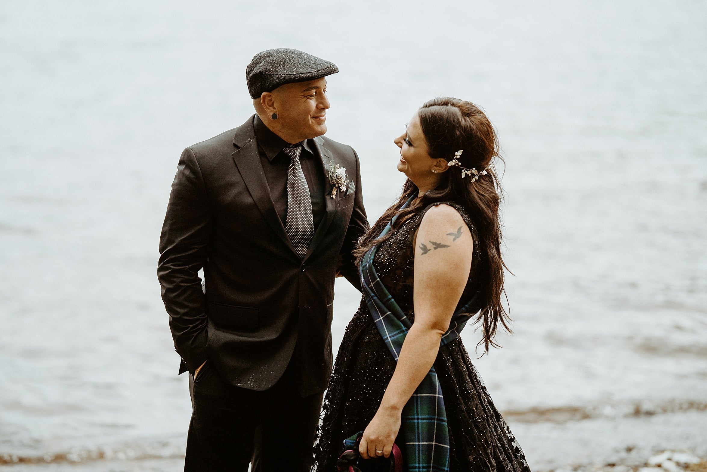bride and groom both wearing black looking lovingly into each others eyes with loch in background monachyle mhor wedding