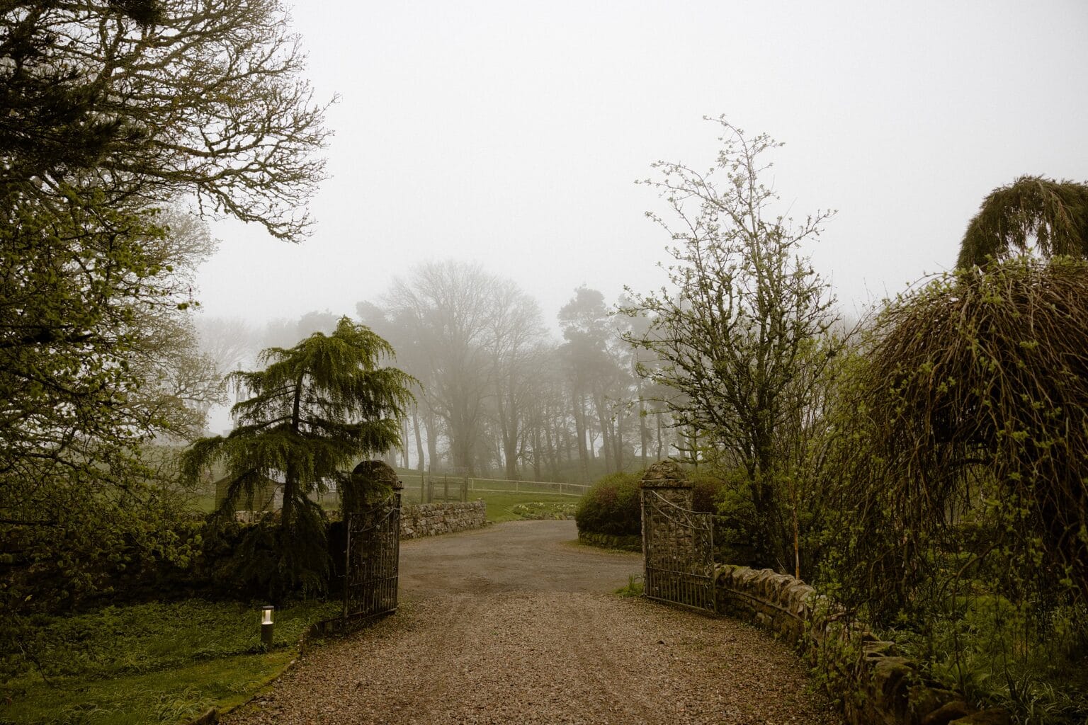exterior outside view of a path and gate at the entrance to barn wedding venues west lothian scotland on a foggy spring morning