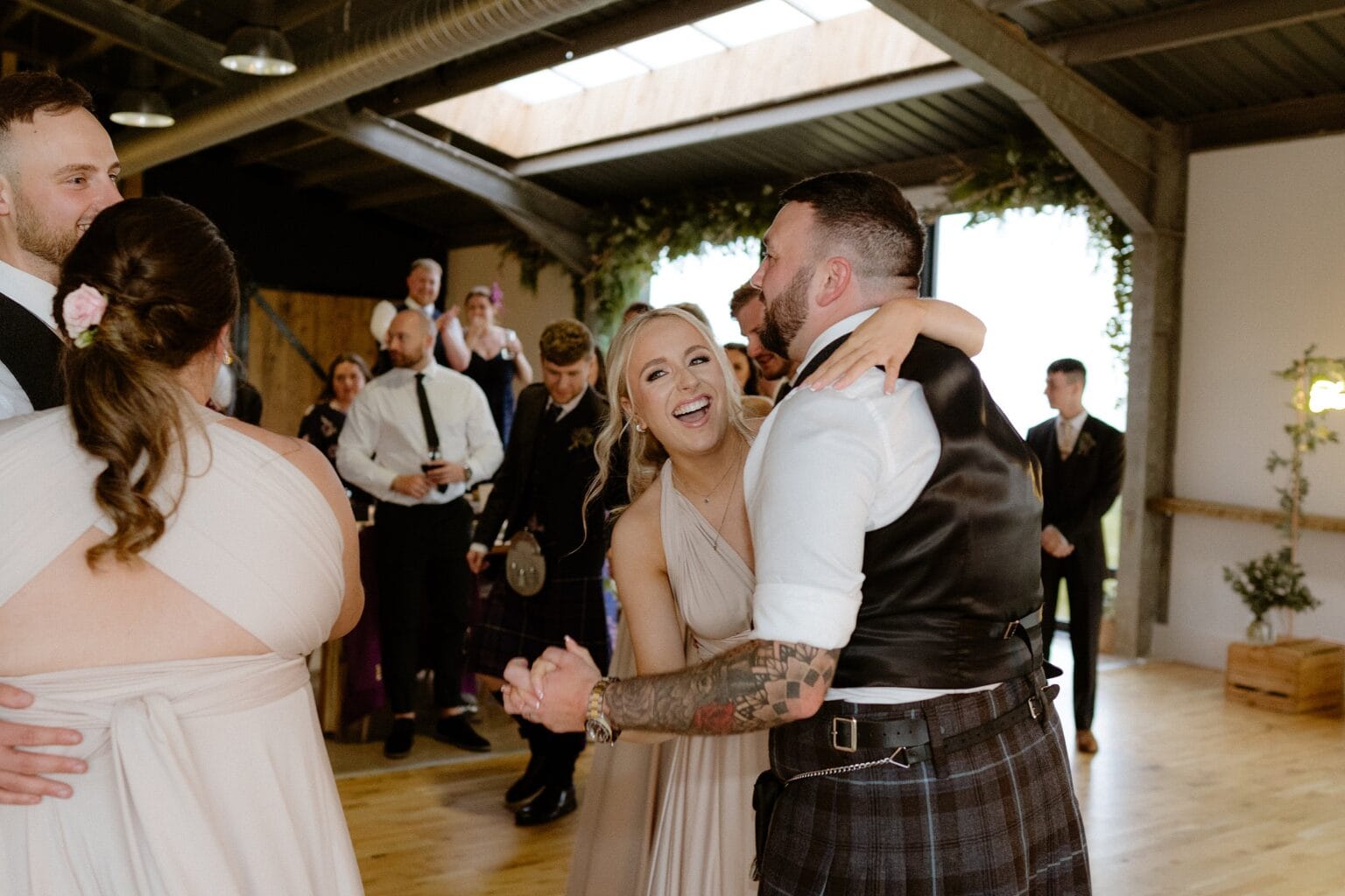 guests dance at the evening reception following the wedding at cairns farm estate in kirknewton in scotland a window surrounded by greenery is visible in the background