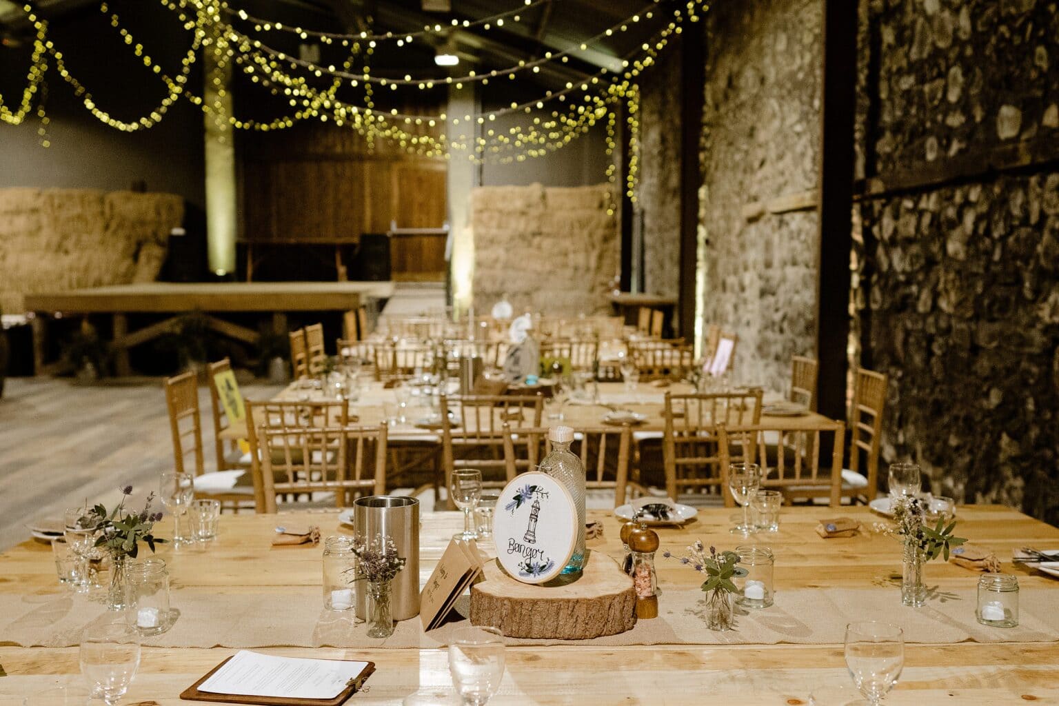 tables set for dinner with festoon lighting hanging above and hay bales in the background at one of the best farm wedding venues scotland