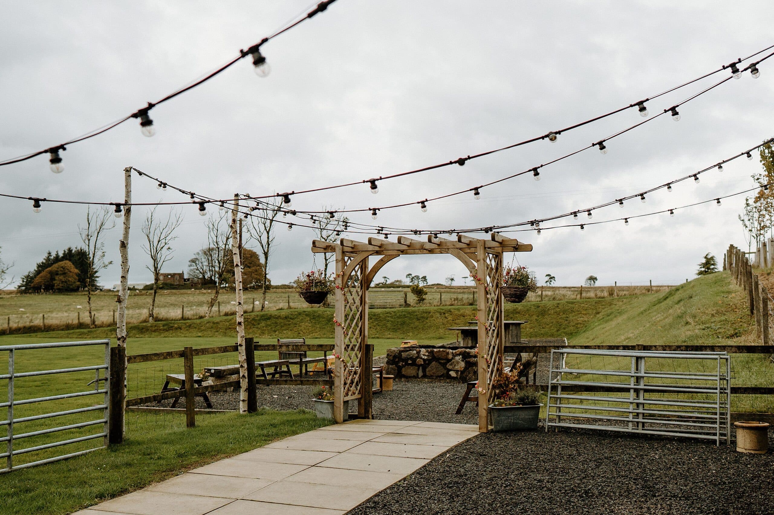 outside exterior view of harelaw farm wedding venue fenwick scotland featuring a wooden arch and festoon lights