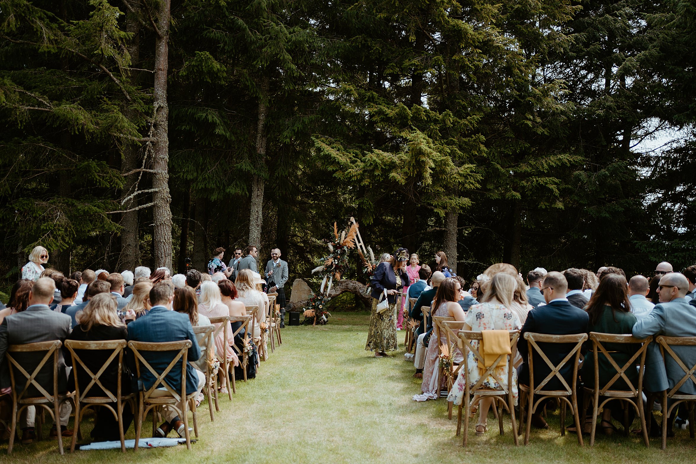 view from back of guests sitting at outdoor ceremony in front of woodland cardney steading