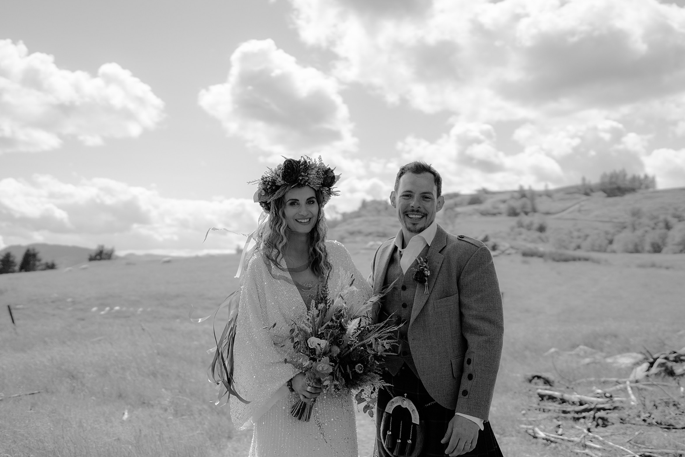 black and white photo of bride and groom standing in grass field with hills in background cardney steading wedding photography