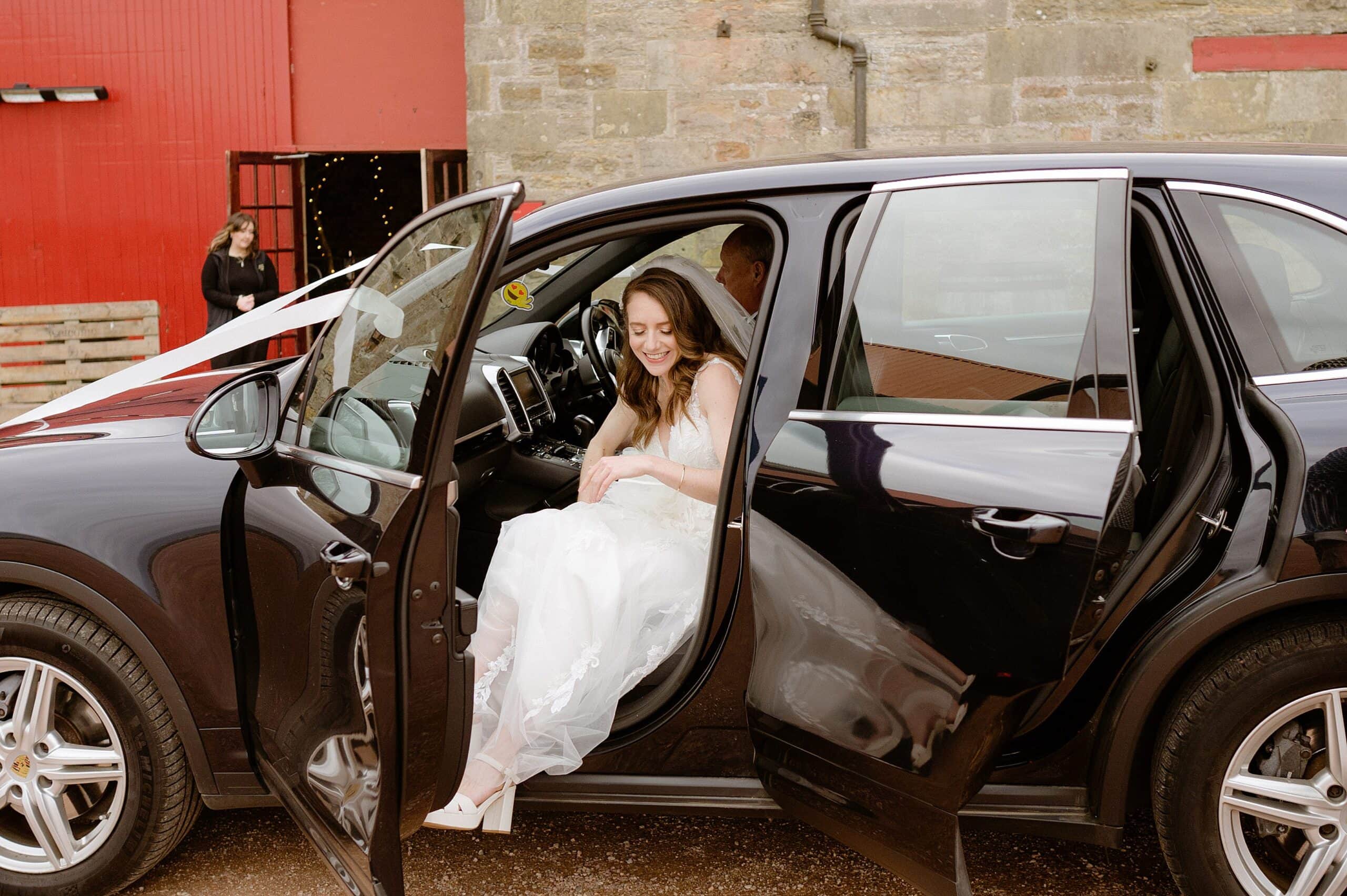 the bride stepping out of the wedding car at a unique barn wedding venue in scotland captured by st andrews wedding photographer