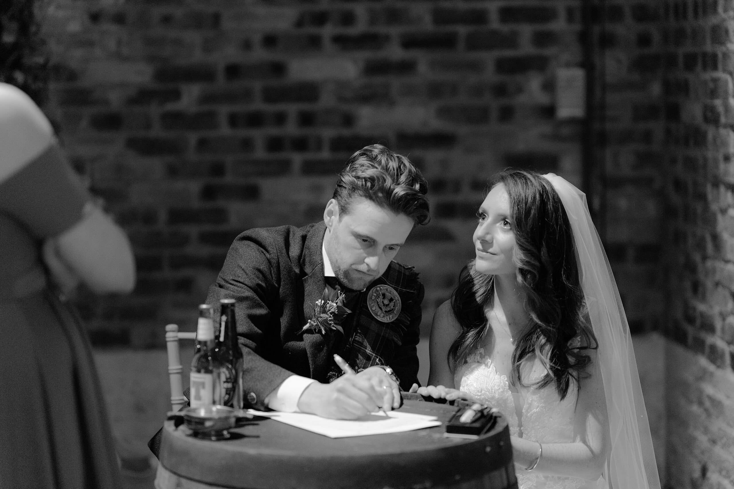 the bride and groom signing the register on an oak barrel following their wedding ceremony in andrews scotland