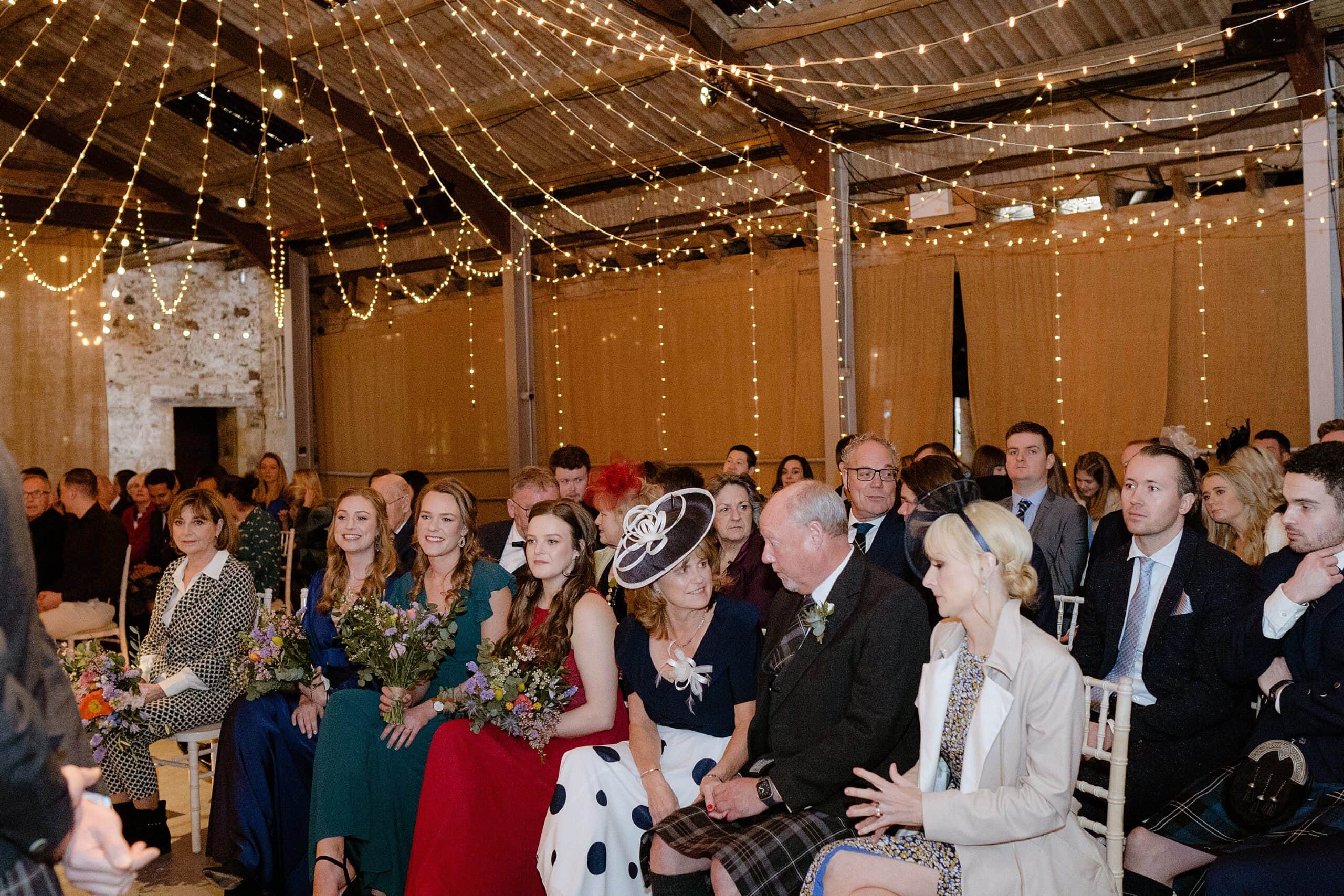 guests seated beneath festoon lights during wedding ceremony at a barn wedding venue in scotland