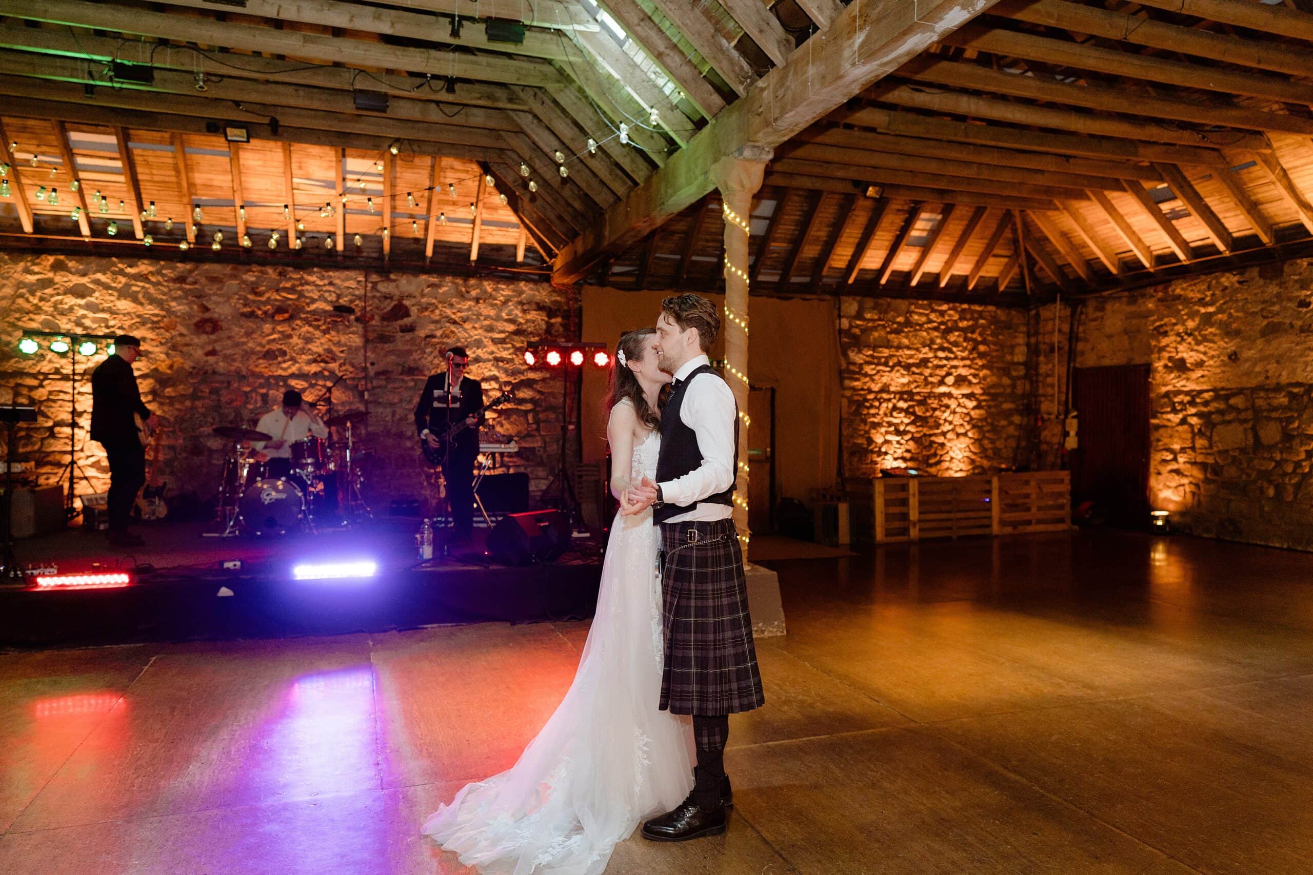 the bride and groom's first dance with a band playing on a stage in the background captured by st andrews wedding photographer
