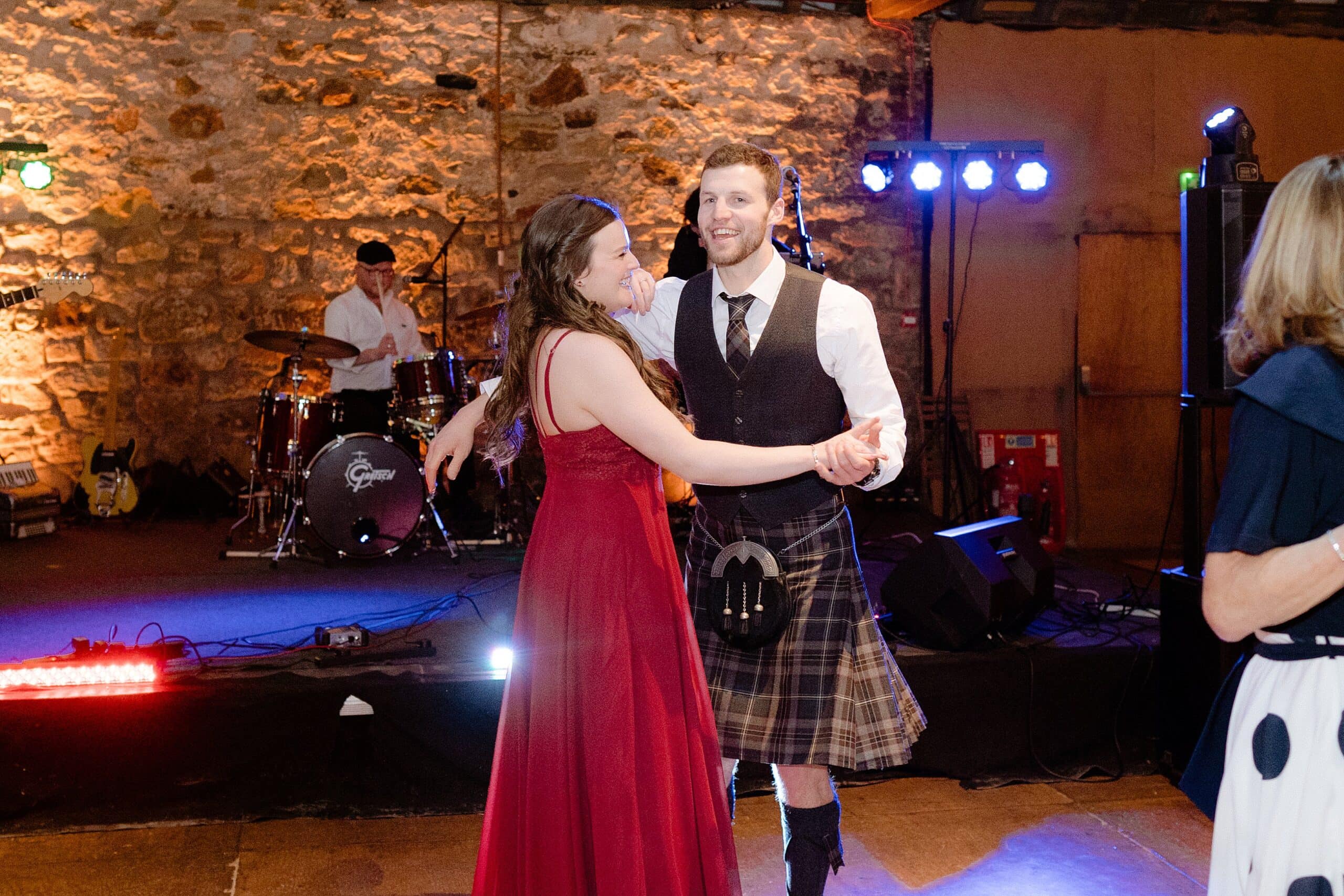 st andrews wedding photographer captures interior inside view of a unique barn wedding venue in scotland showing guests dancing in front of a band playing on a stage