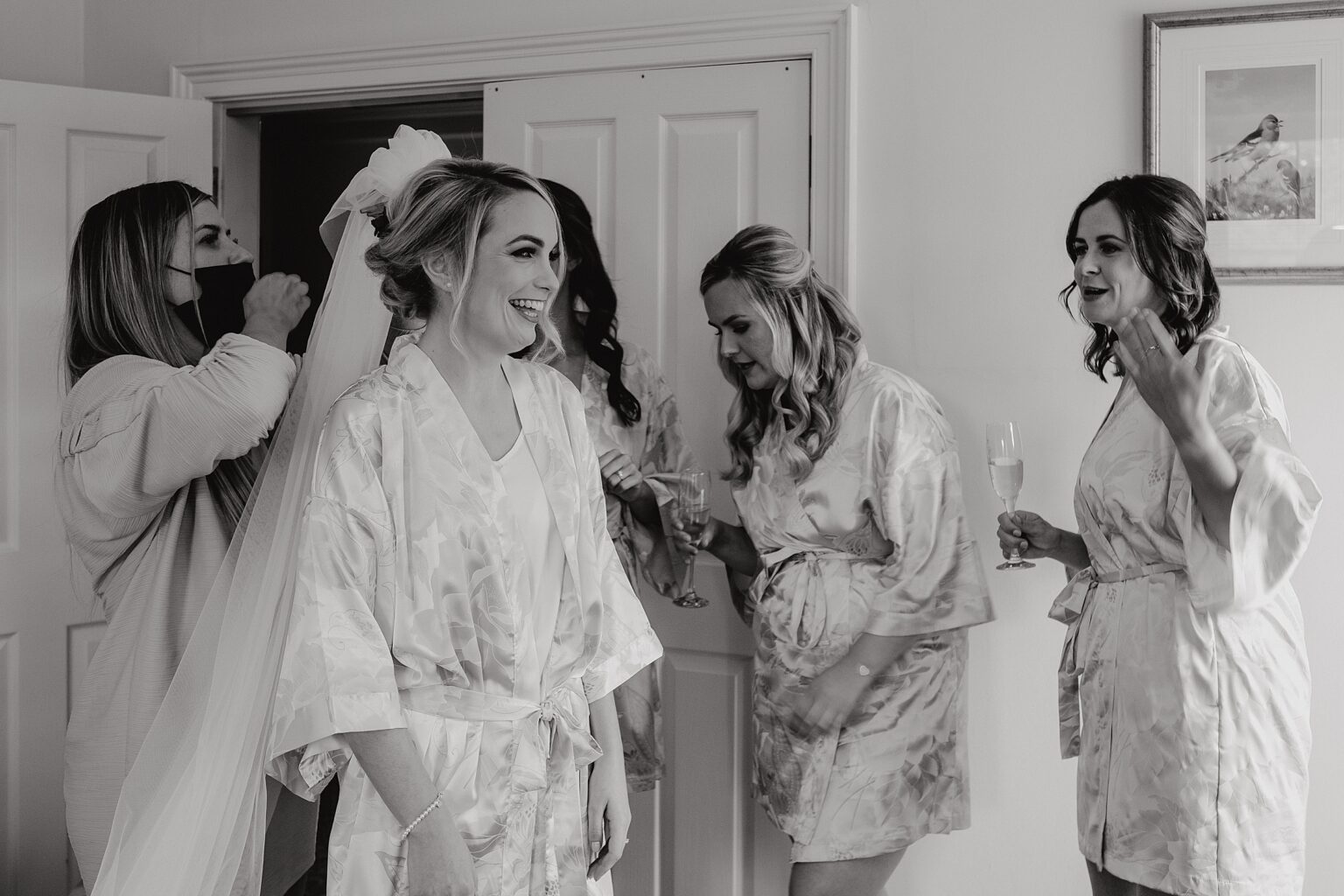 bridesmaids smiling as they drink champagne whilst the bride has her veil put on colstoun house wedding unique wedding venue scotland
