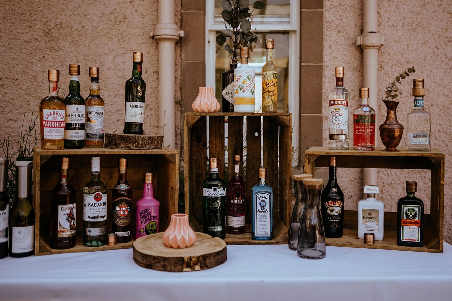close up of drinks table with bottles of spirits in wooden stands colstoun house wedding unique wedding venue scotland