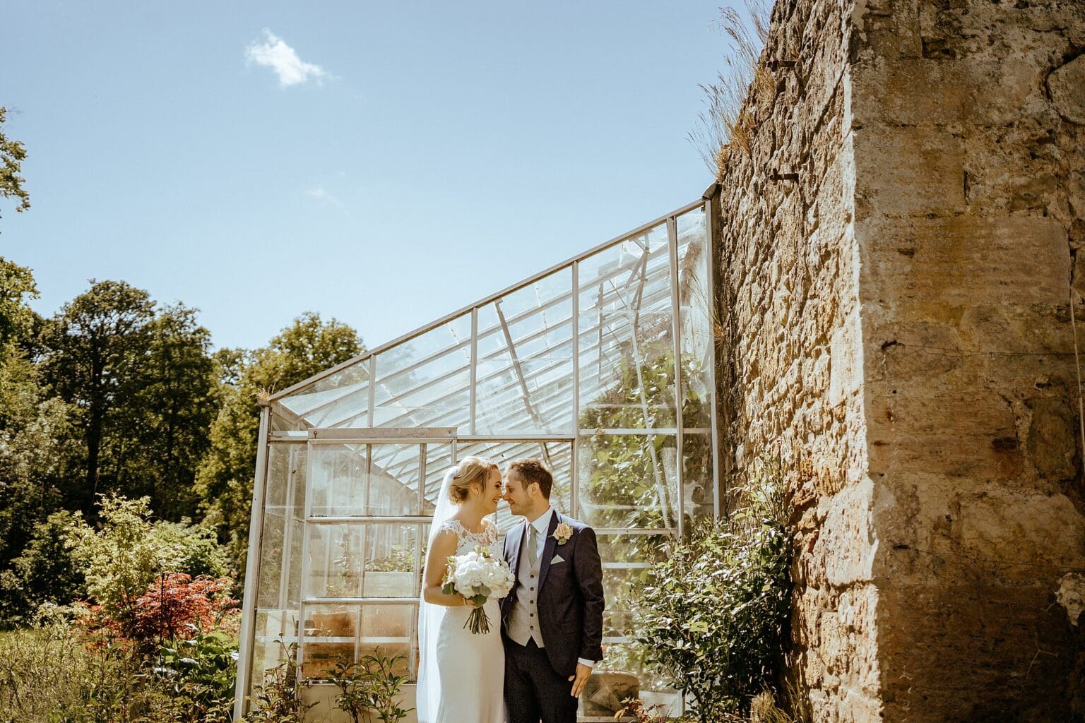 bride and groom facing each other as they stand in front of greenhouse in walled garden colstoun house wedding cost unique wedding venue scotland