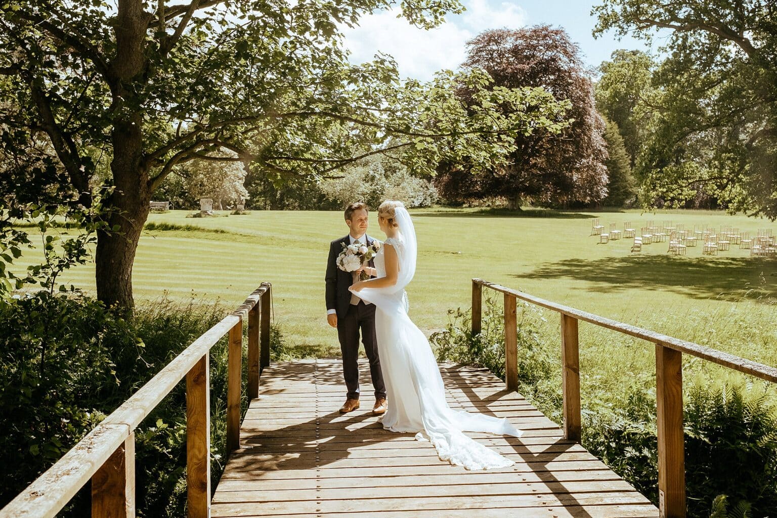 bride and groom standing on small wooden bridge in venue grounds on beautiful sunny day exclusive use colstoun house wedding unique wedding venue scotland