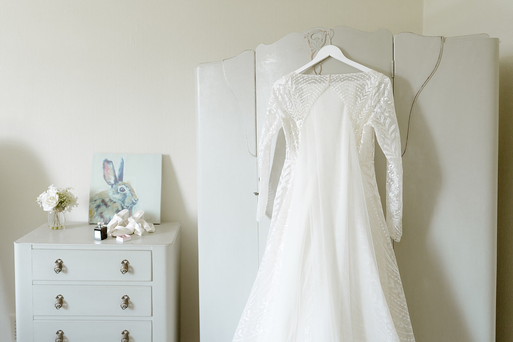 bride's white gown hanging on wardrobe door in bedroom before her the den at Culross wedding