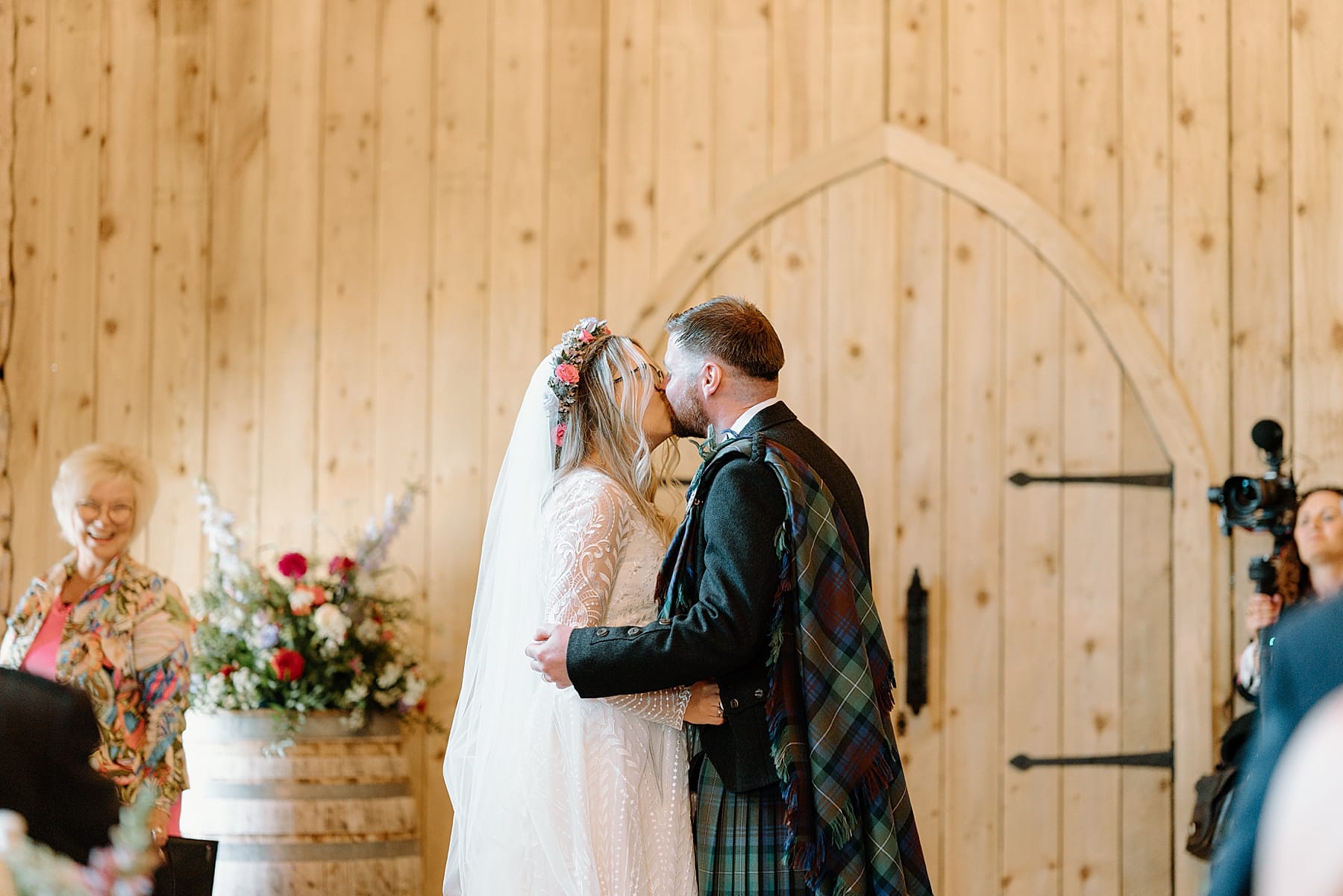 bride and groom kissing in front of wooden barn doors after their ceremony at the den at culross wedding