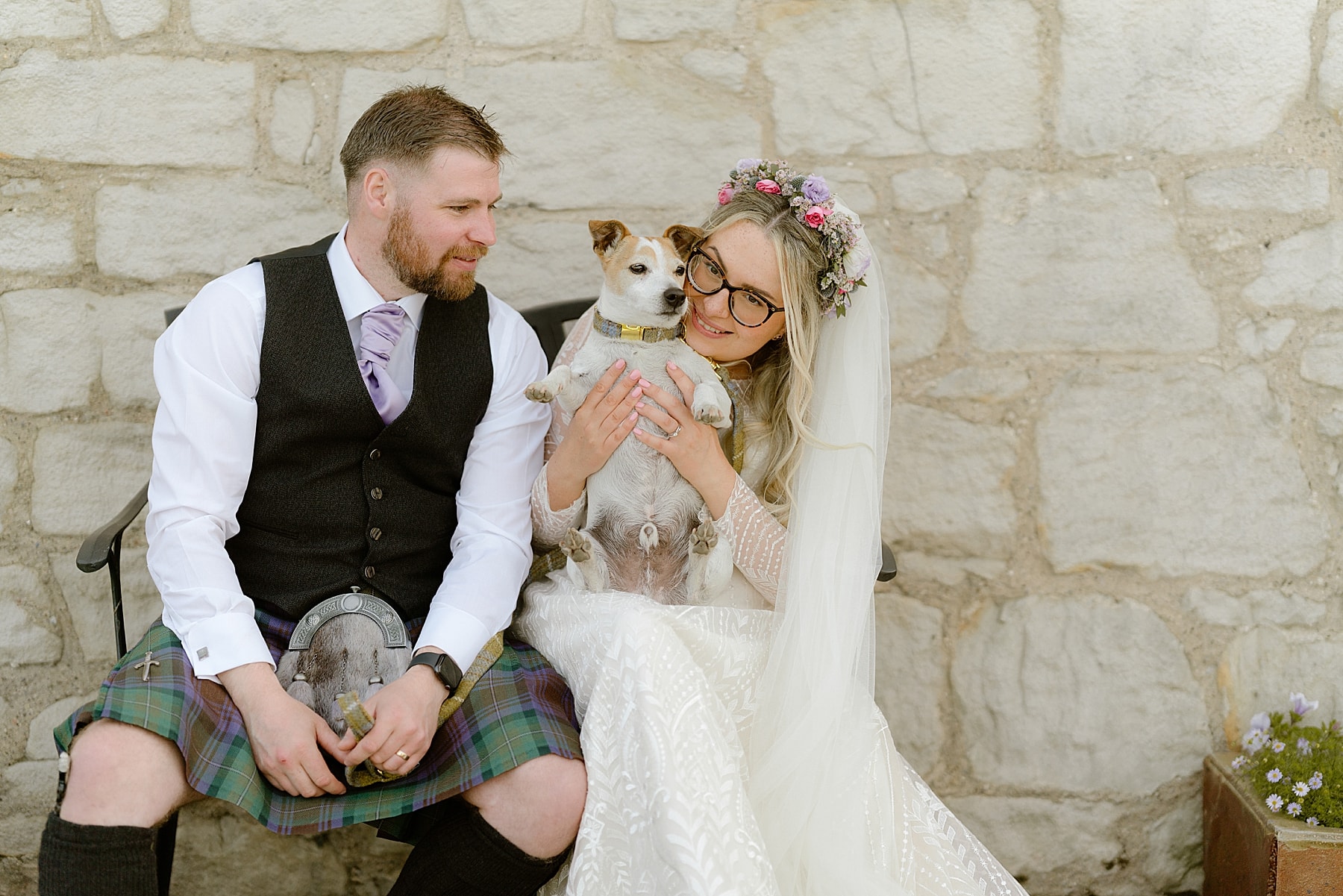 bride and groom with their dog on their wedding day cuddling