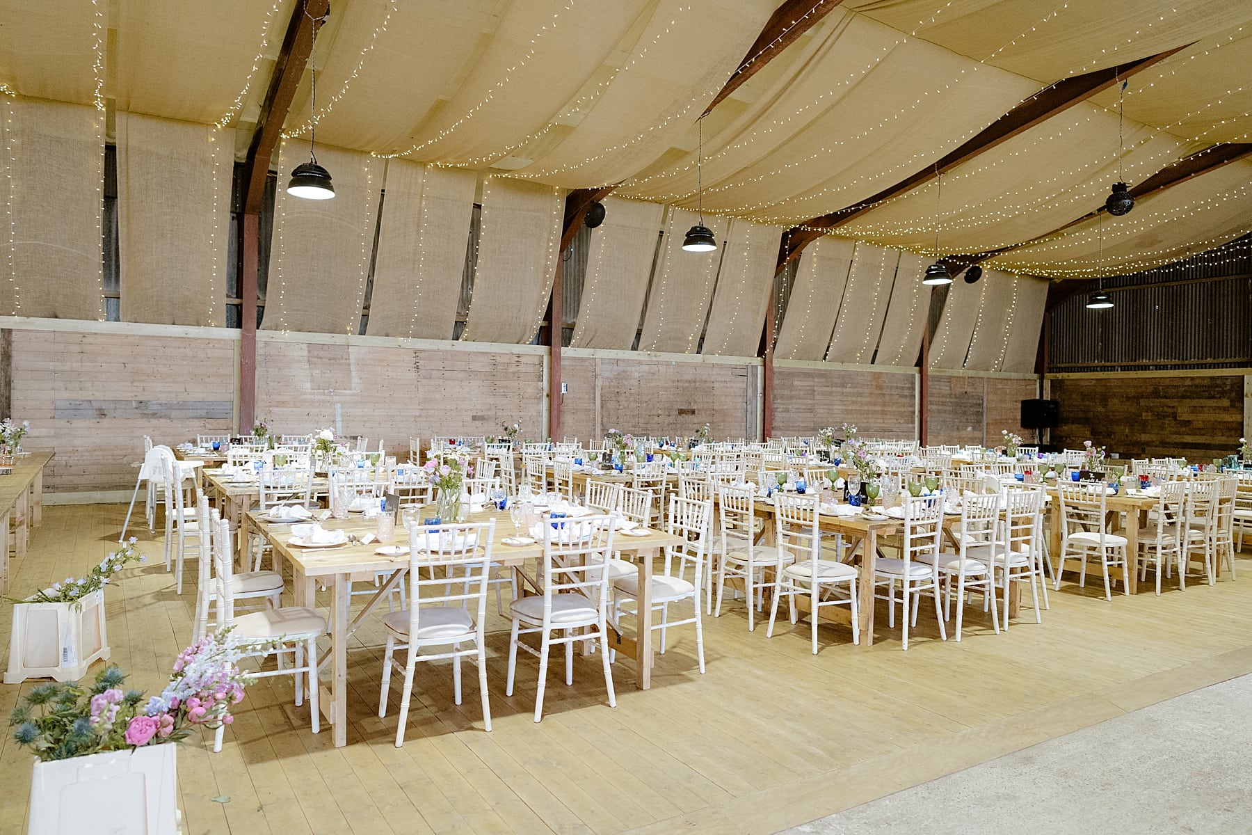 the den at culross wedding reception inside barn with banquet tables with flowers and white chairs