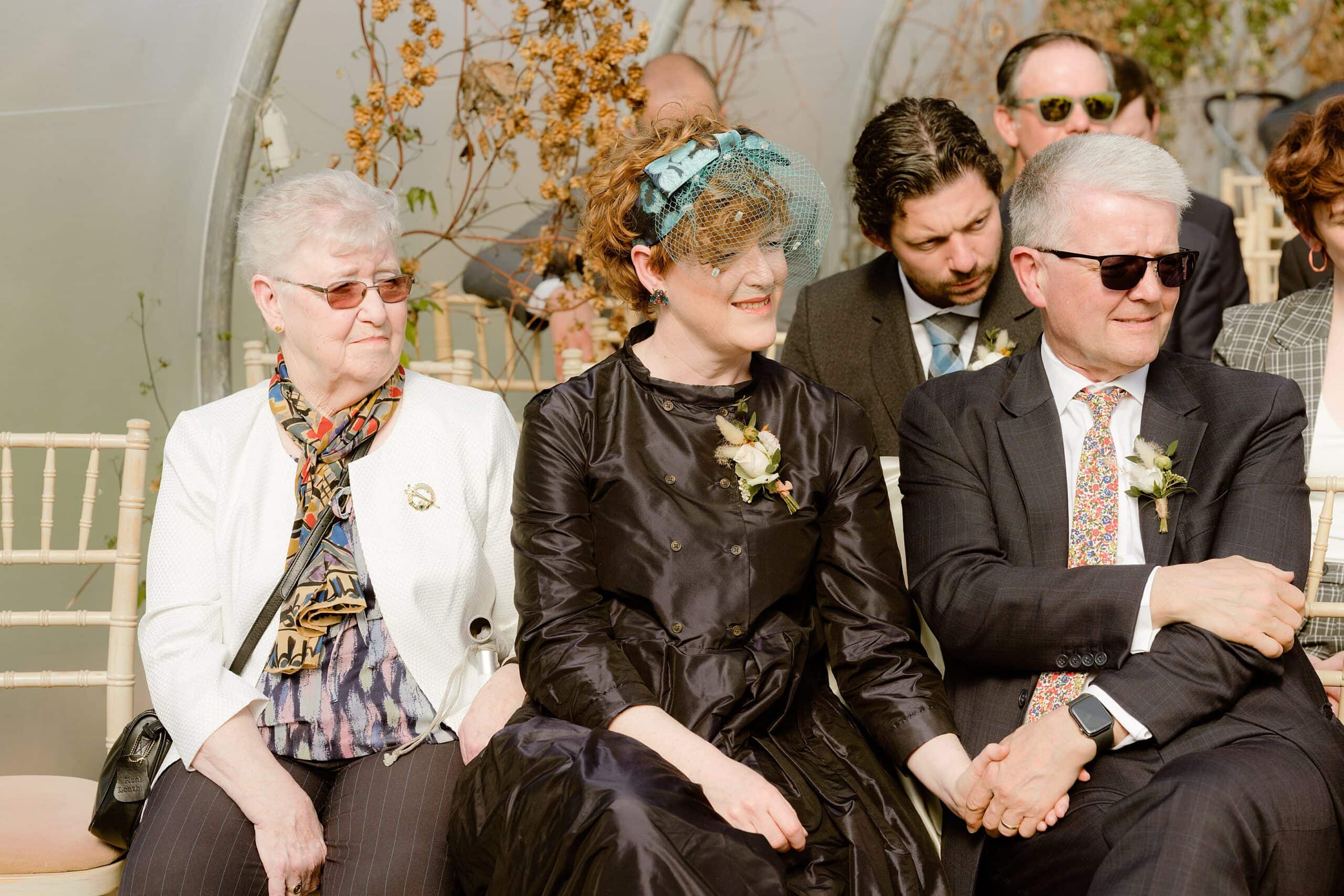 documentary shot of seated guests watching the joyful wedding ceremony in a unique outdoor wedding venue in east lothian in scotland