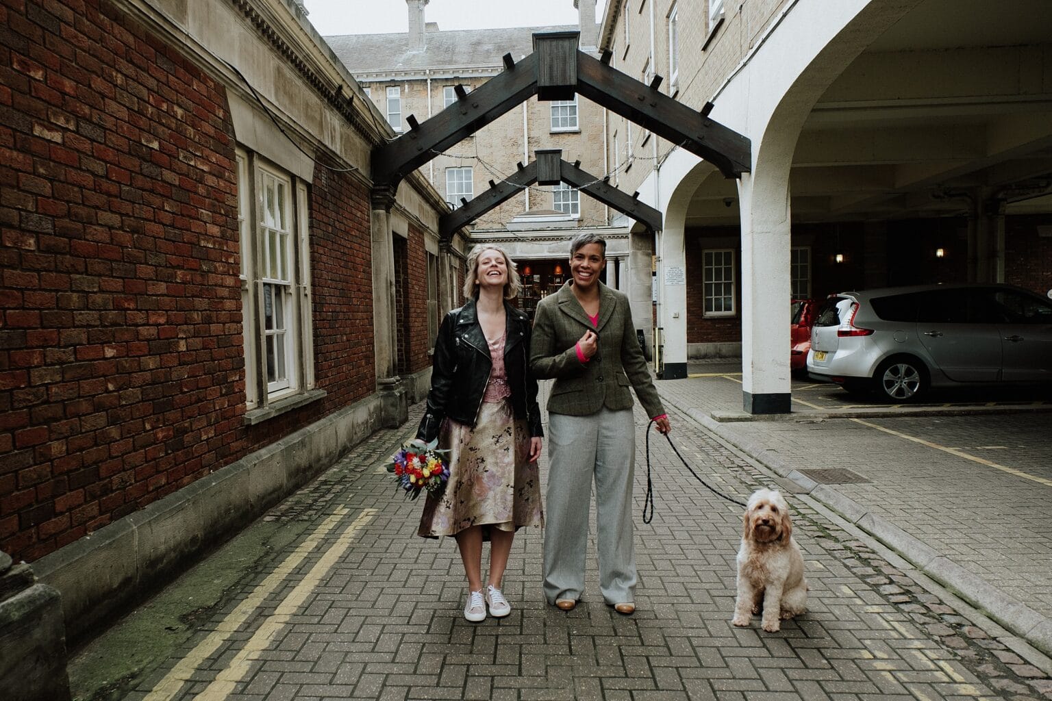 brides posing in city centre lane with their pet dog wedding trends scottish wedding photography